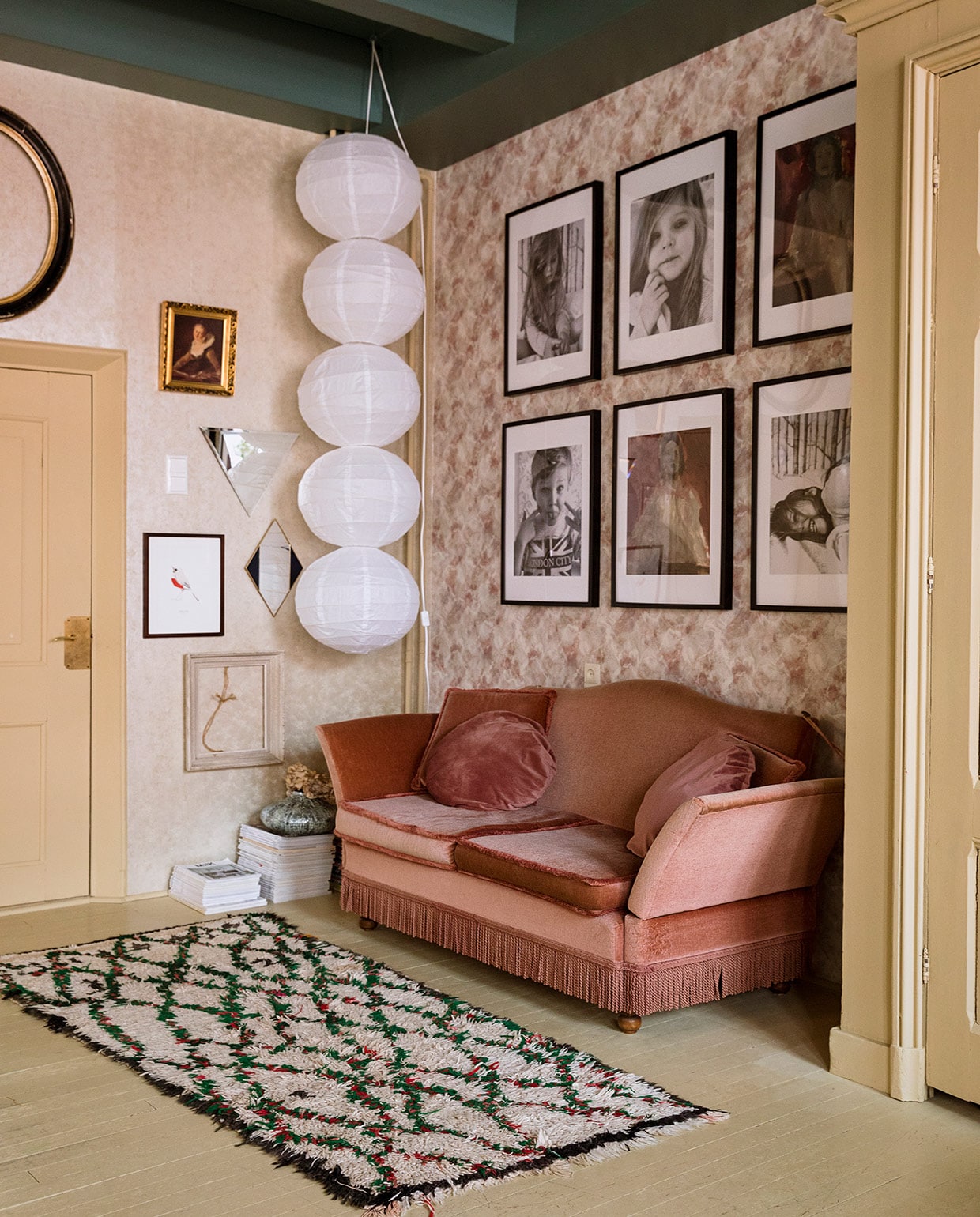 Behang links Fenton in goud en rechts Quartz van 1838 Wallcoverings. Verfkleur plafond Peacock en overig houtwerk Bisquit van Painting The Past. Tweedehands bank gekocht via Instagram. Vloerkleed The Souks. Geometrische spiegels Living Once en &amp;Klevering. Lijsten her en der verzameld. Pot op stapel tijdschriften Loods 5. Bollampen van rijstpapier Ikea, zelf aan elkaar geregen. Ingelijste fotoportretten van de kinderen en schilderijen van Grace Spiegel.