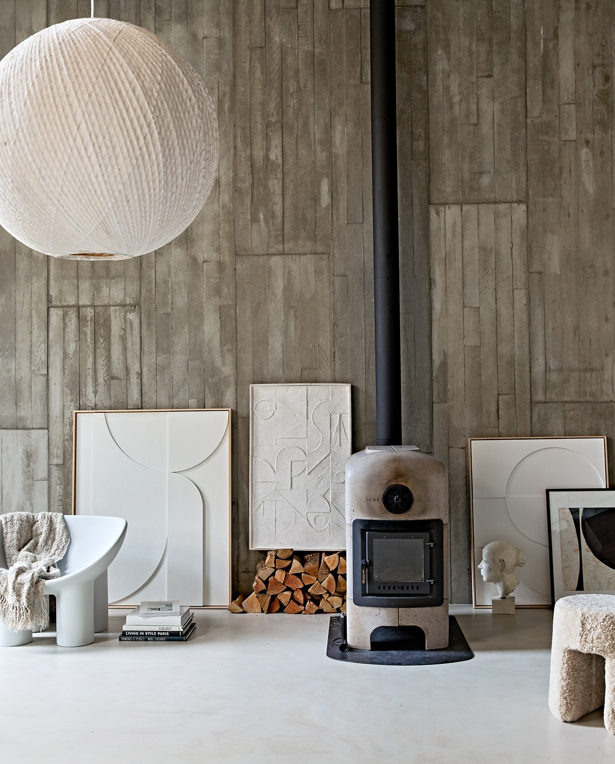 Betonnen houtkachel vanaf € 6500,-(dekleinenvanhoff.nl). Grijze kunststof stoel Roly Poly van Driade € 410,- (kmpkantoormeubilair.nl). Papieren-bamboe hanglamp Bali, 80 cm (Ø) € 695,-, grote kunstlijst met wit reliëf 123x100x4 cm (lxbxd) € 629,-, kunstlijst wit rechts naast de kachel, 83x62x4 cm (lxbxd) € 449,-, linnen plaid 130×170 cm € 169,95 (hkliving.nl). Lijst met reliëfkunst op stapel hout € 199,- (urbannatureculture.nl). Zwart-witte collage, ingelijst, prijs op aanvraag (artinreturn.nl). Wit object vrouwenhoofd (vintagehoarder.com). Poef Sequoia bekleed met schapenvacht van Fredericia, 40×42 cm (Øxh) vanaf € 865,-(designtales.nl).