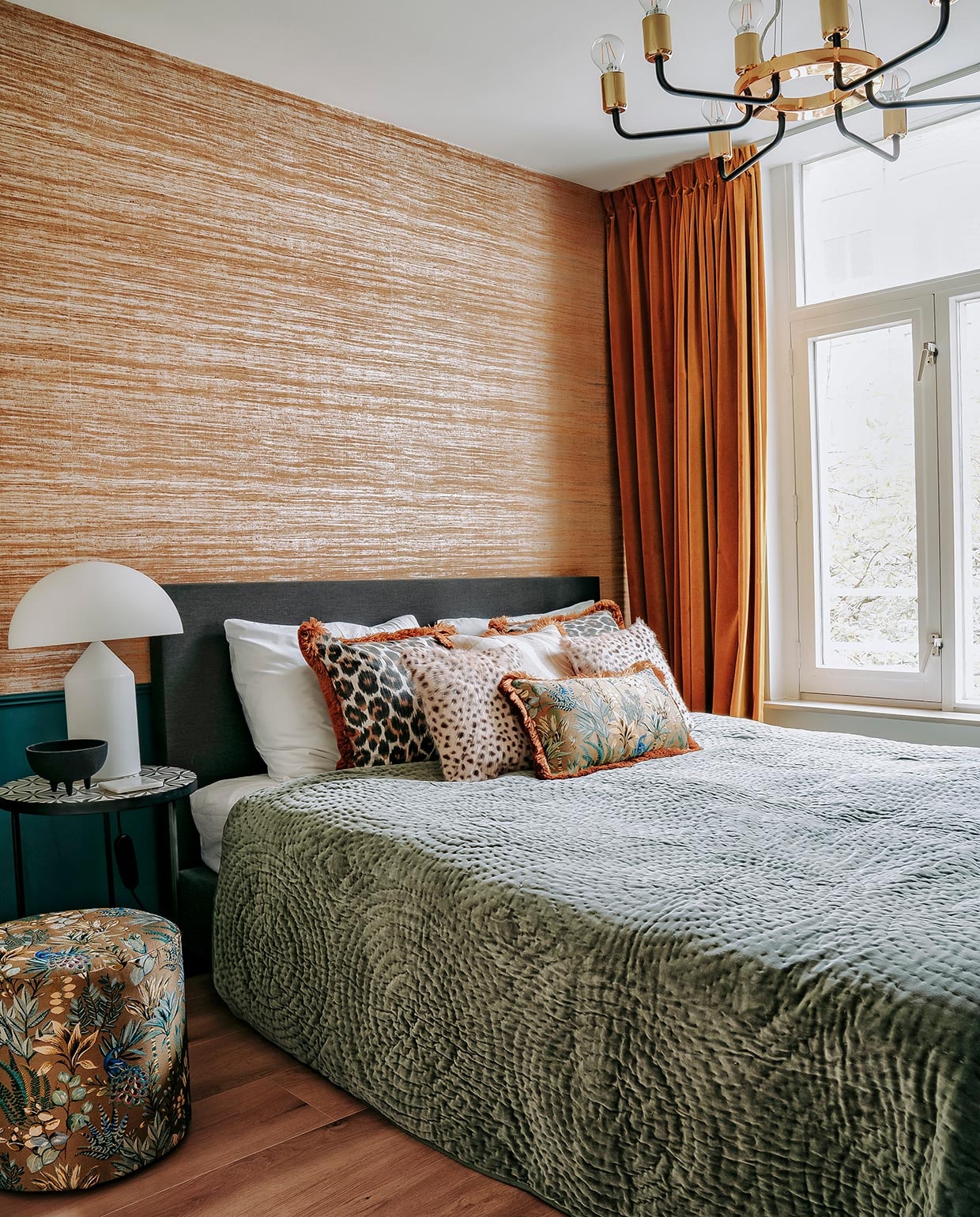 Poef, bijzettafel, schaaltje, panterprint en overige kussens en sprei Nox Studio Interiors. Witte lamp Oluce, hanglamp Westwing. Verf op lambrisering Inchyra Blue van Farrow &amp; Ball, behang Arte. Bed Wehkamp, hoofdkussens Hema, gordijnen Dappermarkt.