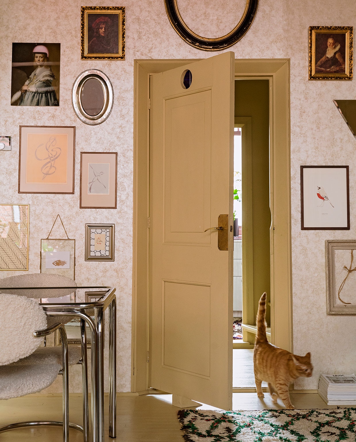 Behang Fenton in goud van 1838 Wallcoverings. Verfkleur houtwerk Bisquit van Painting The Past. Vintage tafel en stoelen Living Once, zelf gestoffeerd. Vloerkleed The Souks. Verzameling lijsten erfstukken, cadeau gekregen en kringloopwinkel. Print Meisje in het blauw met roze helm Arti-shock, print roodborstje Maartje van den Noort, overige herkomst onbekend.
