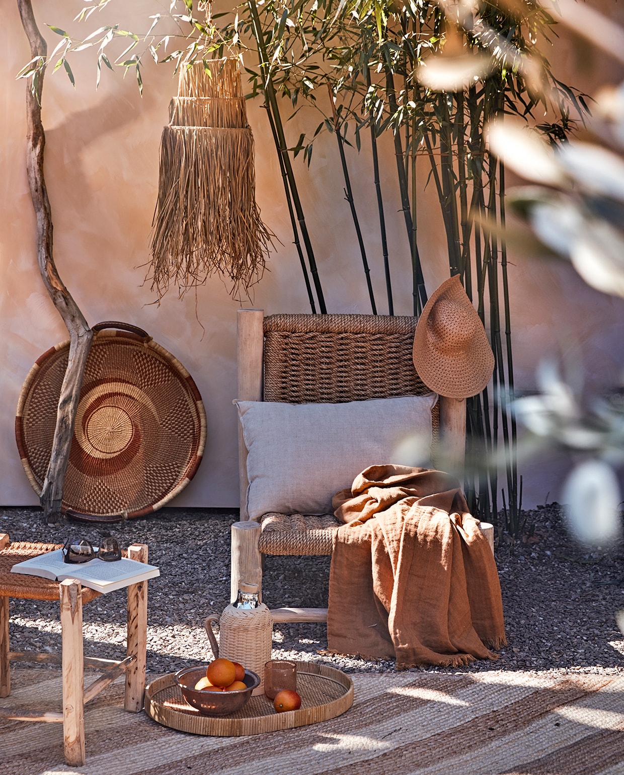 Muur geschilderd met buitenverf Kalei in Sahara Dust van Pure &amp; Original, per 5 liter (deruamsterdam.nl). Stoel Charlotte, amberkleurig linnen plaid, muurmand Ghana, olijfhouten kruk met oranje zitting, 45×45 cm (couleurlocale.eu). Vloerkleed van Madam Stoltz, 200×140 cm, rieten lampenkap (deens.nl). Rieten thermoskan, glas, dienblad (nordal.eu). Naturel linnen kussen van vtwonen, 50×70 cm (vtwonen.nl). Overig privébezit.