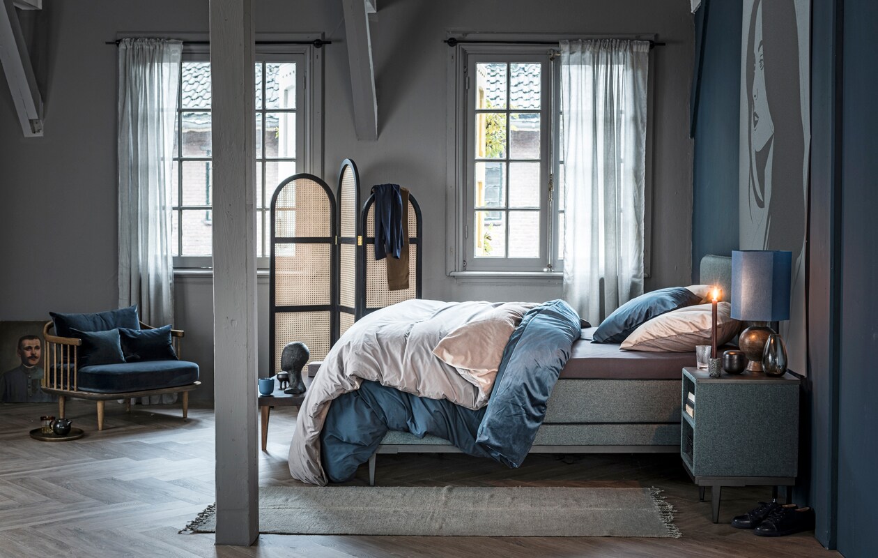 Boxspring Pepper in stof Tweed kleur Moss Green en poten Angle in kleur antraciet, 140×200 cm (bxl). Nachtkastje Cumin met stof Tweed in kleur Moss Green en poten Angle in kleur antraciet, 45×45 cm.M.m.v.: vtwonen collectie (vloerkleed, dekbedovertrekken en gordijnen), &amp;Tradition (fauteuil), Pols Potten (dienblad, glas), Wildschut Antiques (schilderij), HK Living (kamerscherm, houten hoofd, tafellamp met blauw kap), Norr11 (houten bank). Overig privébezit.