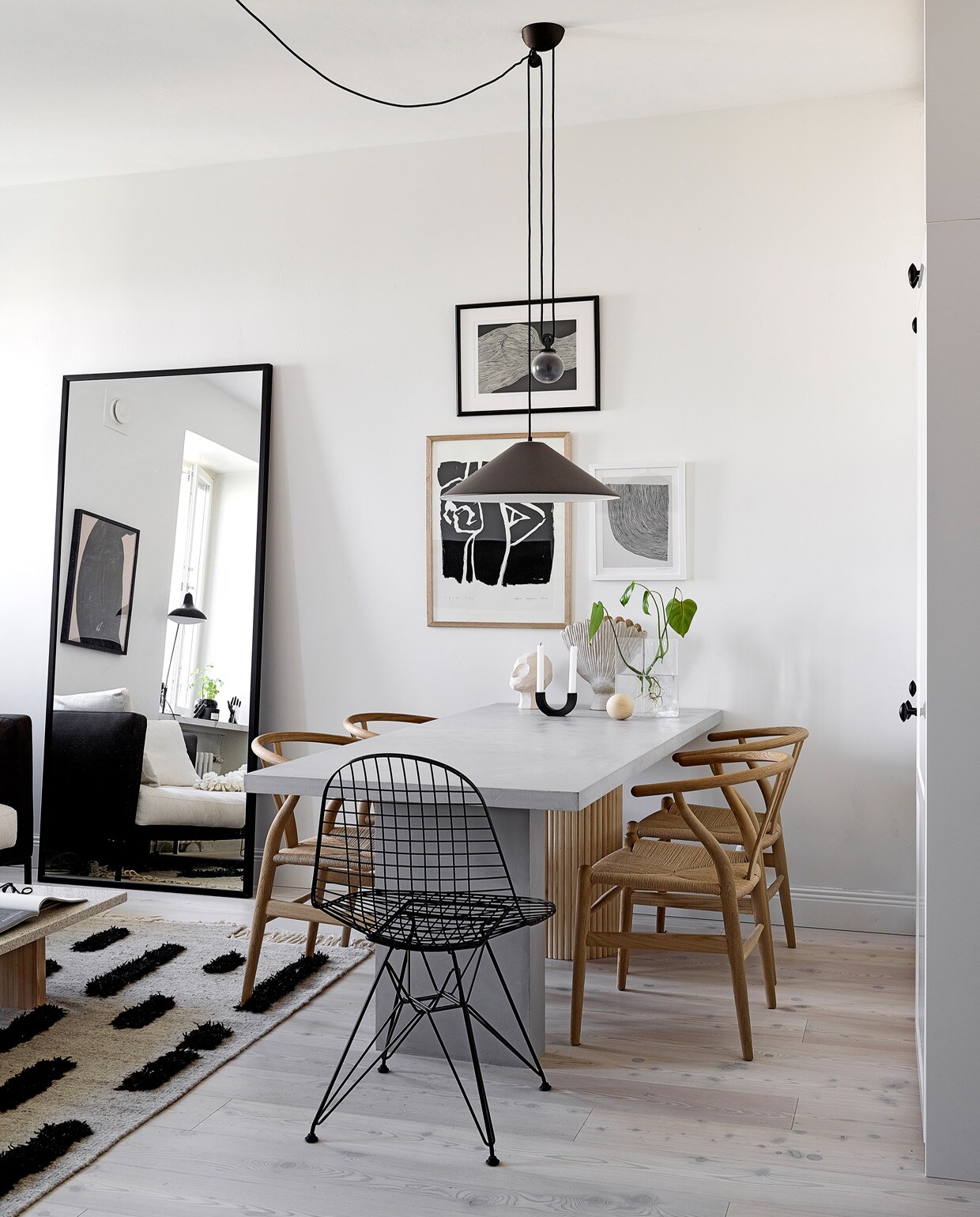 Vloer Timberwise. Spiegel eigen ontwerp, gemaakt door Essis Collection. Vloerkleed Sera Helsinki. Eettafel Bond eigen ontwerp, verkrijgbaar via Decorativi Design. Eetkamerstoelen Wishbone Carl Hansen &amp; Son. Draadstalen stoel Eames DKR Vitra. Keramieken hoofd Kristiina Haataja, ronde kandelaar Ferm Living, keramieken vaas Samuji, glazen vaas Iittala. Hanglamp Aggregato Saliscendi Artemide. Posters The Poster Club.