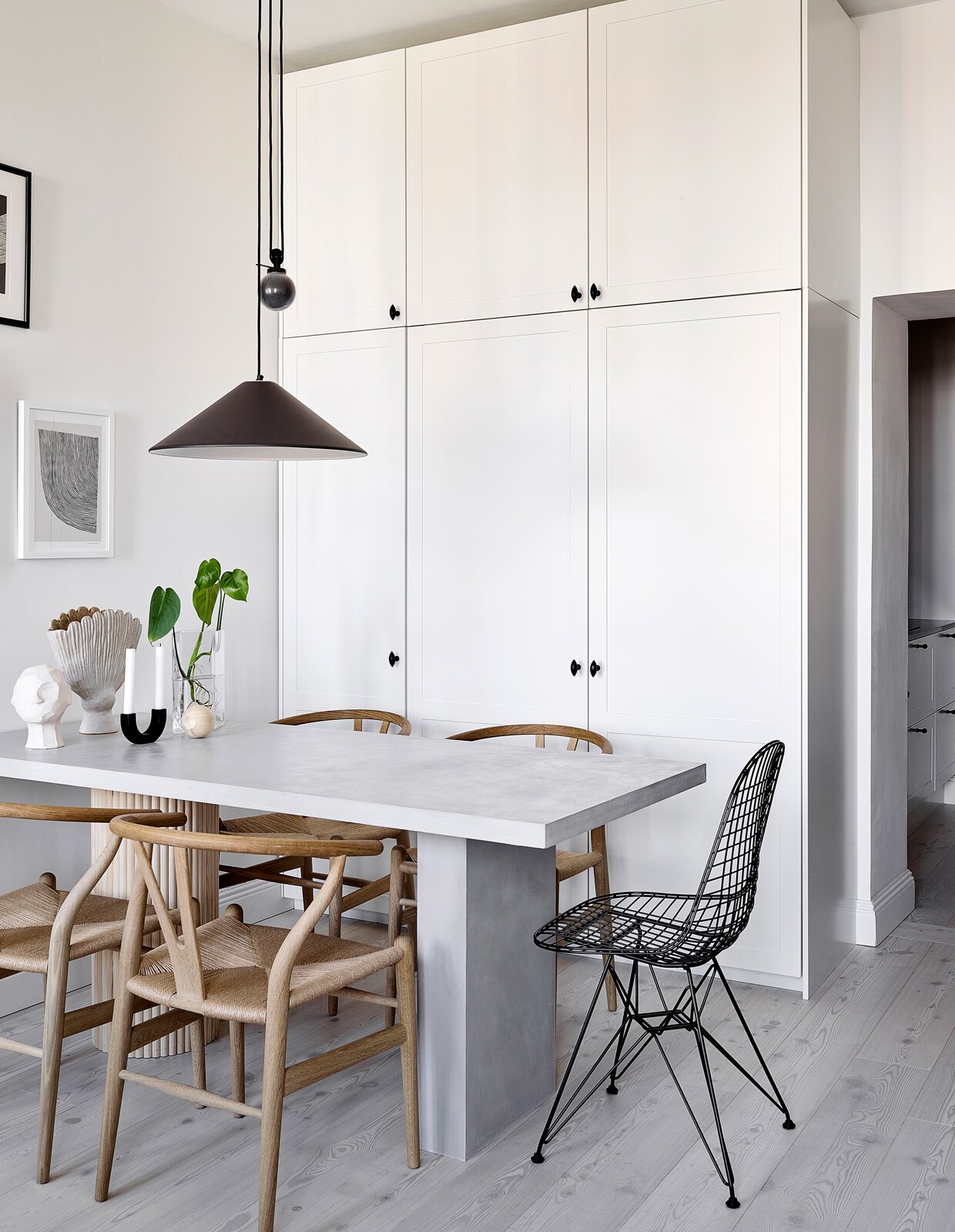 Vloer Timberwise. Spiegel eigen ontwerp, gemaakt door Essis Collection. Vloerkleed Sera Helsinki. Eettafel Bond eigen ontwerp, verkrijgbaar via Decorativi Design. Eetkamerstoelen Wishbone Carl Hansen &amp; Son. Draadstalen stoel Eames DKR Vitra. Keramieken hoofd Kristiina Haataja, ronde kandelaar Ferm Living, keramieken vaas Samuji, glazen vaas Iittala. Hanglamp Aggregato Saliscendi Artemide. Posters The Poster Club.