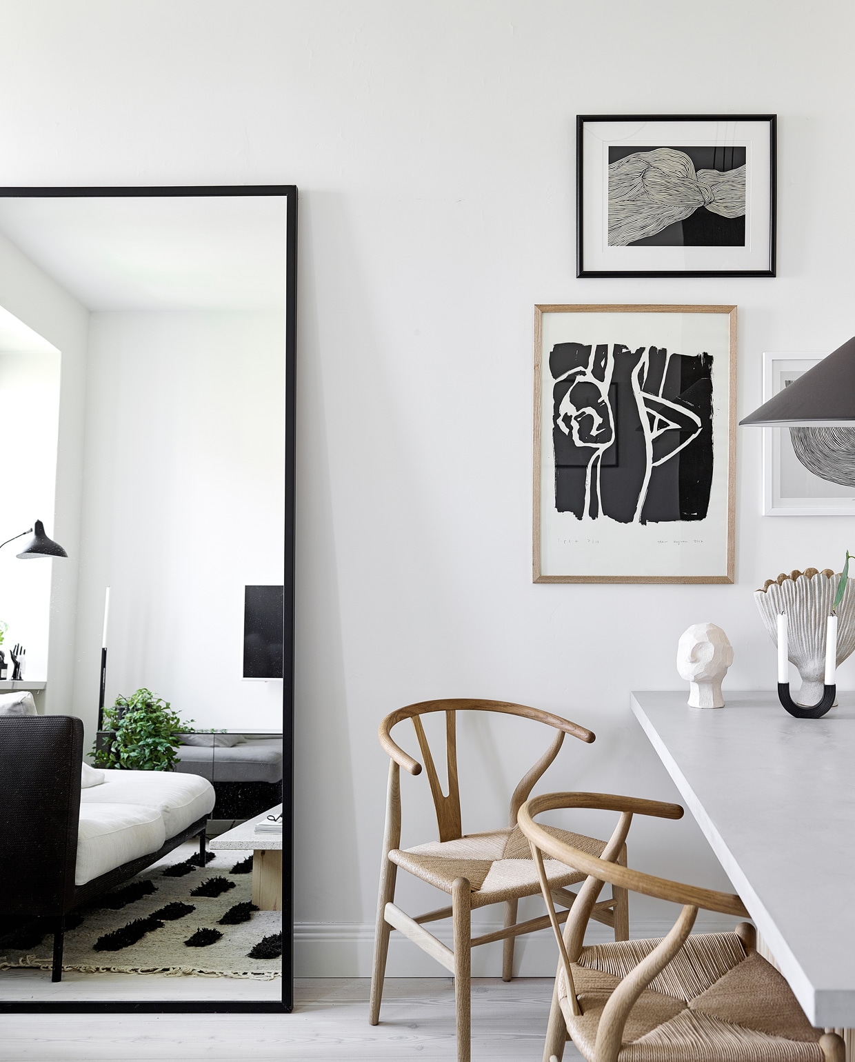 Vloer Timberwise. Spiegel eigen ontwerp, gemaakt door Essis Collection. Vloerkleed Sera Helsinki. Eettafel Bond eigen ontwerp, verkrijgbaar via Decorativi Design. Eetkamerstoelen Wishbone Carl Hansen &amp; Son. Draadstalen stoel Eames DKR Vitra. Keramieken hoofd Kristiina Haataja, ronde kandelaar Ferm Living, keramieken vaas Samuji, glazen vaas Iittala. Hanglamp Aggregato Saliscendi Artemide. Posters The Poster Club.