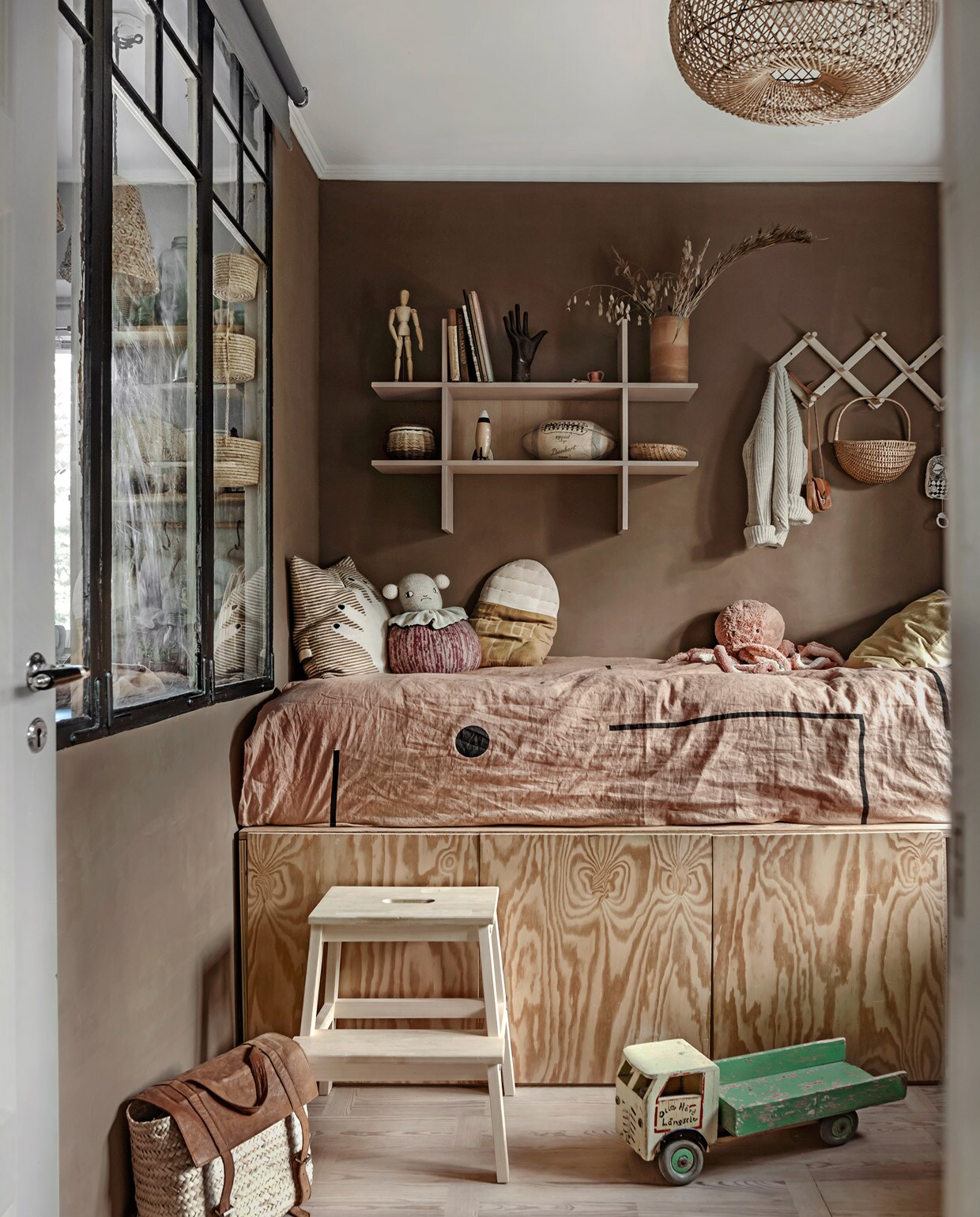 Bed met bergvakken zelfgemaakt, sprei uit Los Angeles, vergelijkbare muurkleur Colosseum van Carte Colori, wandrek en kruk Ikea, kussens Lucky Boy Sunday en Camomile London, mand vintage, vest Poudre Organic, speelgoed vintage.