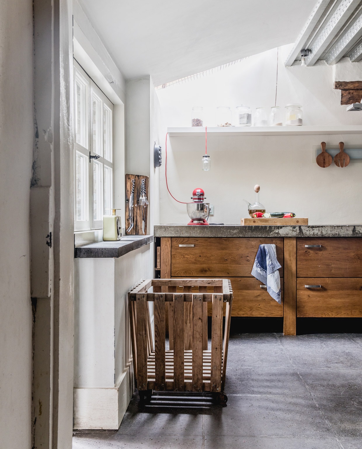Betontegelvloer Schellevis ingewreven met Oxan olie. Keuken ontworpen en gemaakt door Jan en zoon Ruben. Oude wasmand afkomstig uit een hotel. Keukenmachine KitchenAid. Weegschaal Emmaus. Bestekrek zelfgemaakt van oude spoorbiels. Bestek meegenomen uit Frankrijk. Hanglamp zelfgemaakt van jampot en rood snoer van Snoerboer. Houten lepel en vork cadeau gekregen. Vintage oliekan uit Spanje. Overig herkomst onbekend.