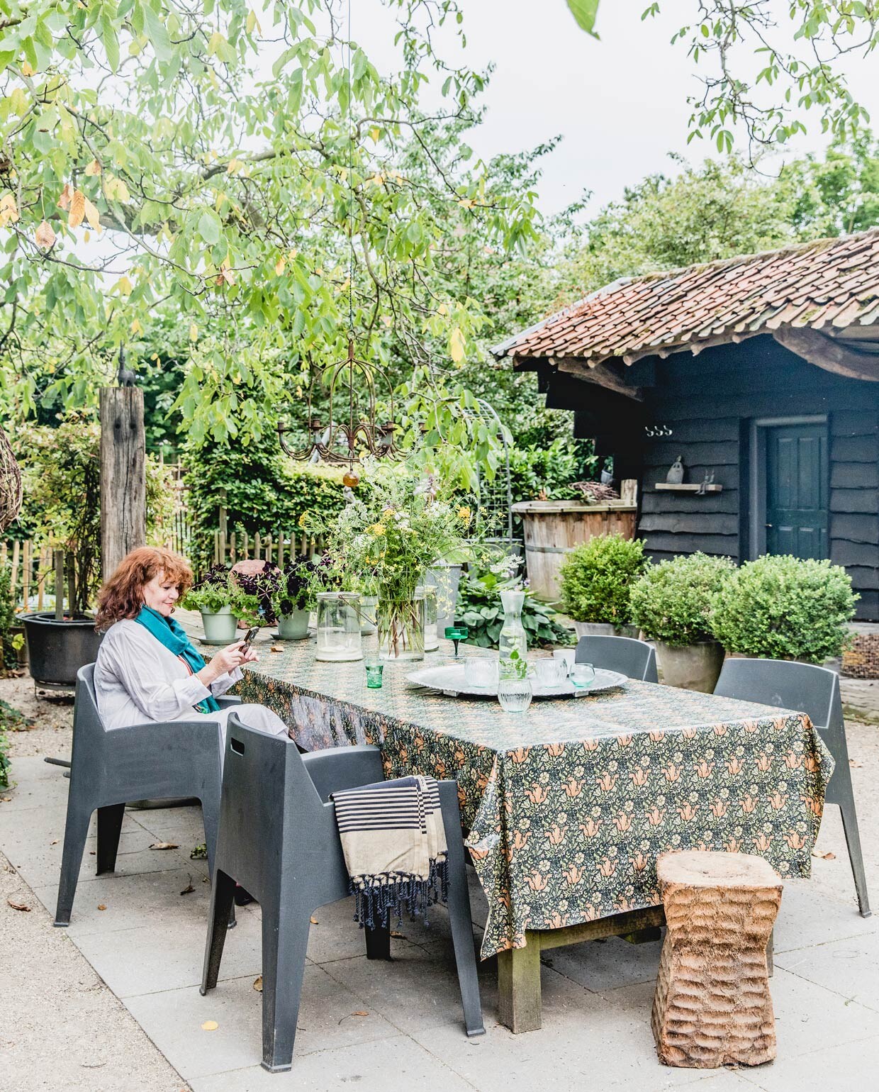 Houten buitentafel gemaakt door Jan. Weerbestendig tafelkleed William Morris. Tuinstoelen Leen Bakker. Pilaar Emmaus. Overig herkomst onbekend.