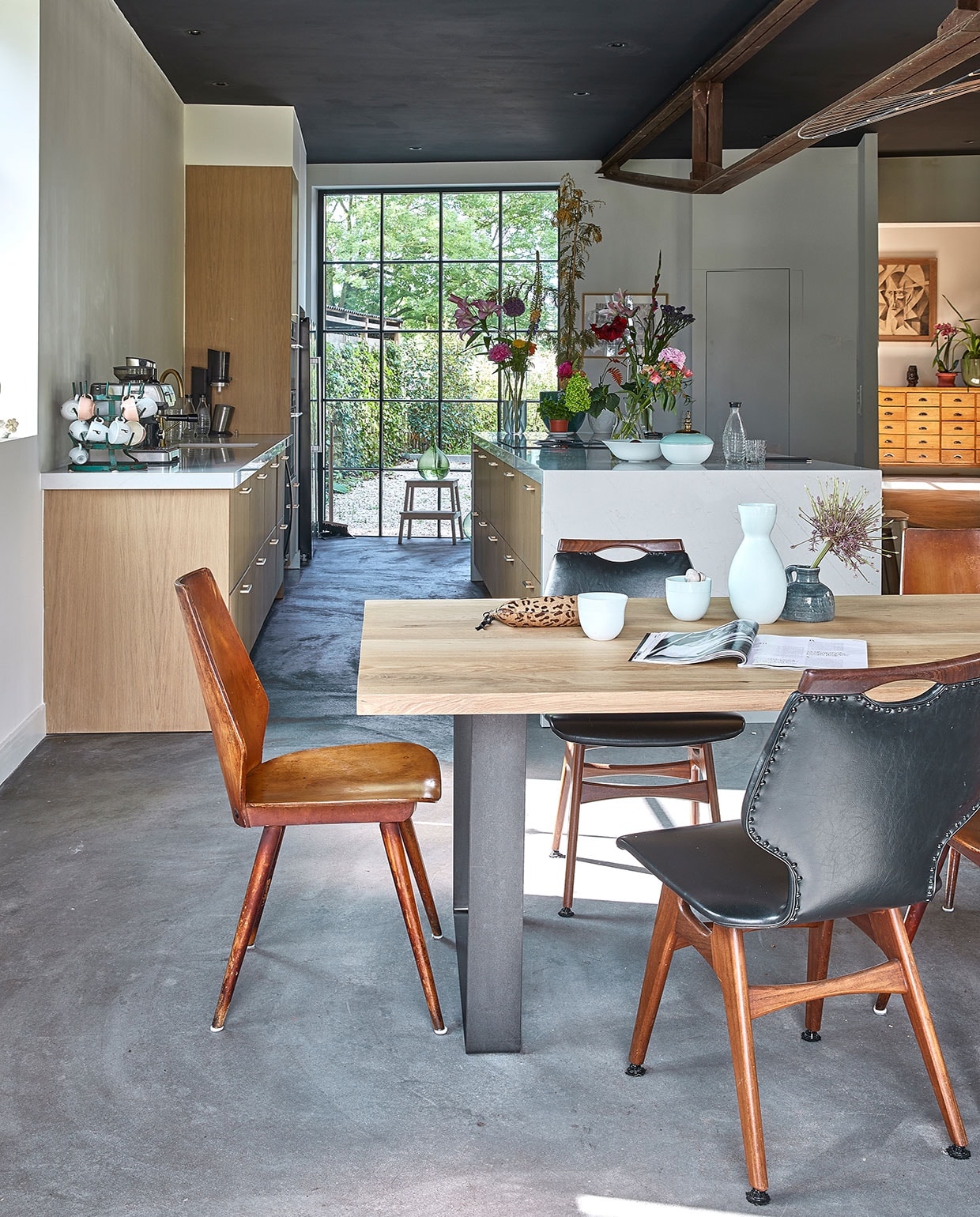 Tafel Houthandel Woerden, stoelen kringloop en brocante. Mokken, witte vaas en witgroene vaas Design Studio Carola Zee. Etui Mango, groene vaas Action. Keuken Ikea, blad Kemie, fronten K14. Schaal en waterkaraf Sodastream, glas en kruk Ikea. Vazen door de jaren heen verzameld, bloemen The Flower Factory. Groene vaas op kruk vintage. Verf plafond grafietzwart Ral 9011. Vloer zandcement.