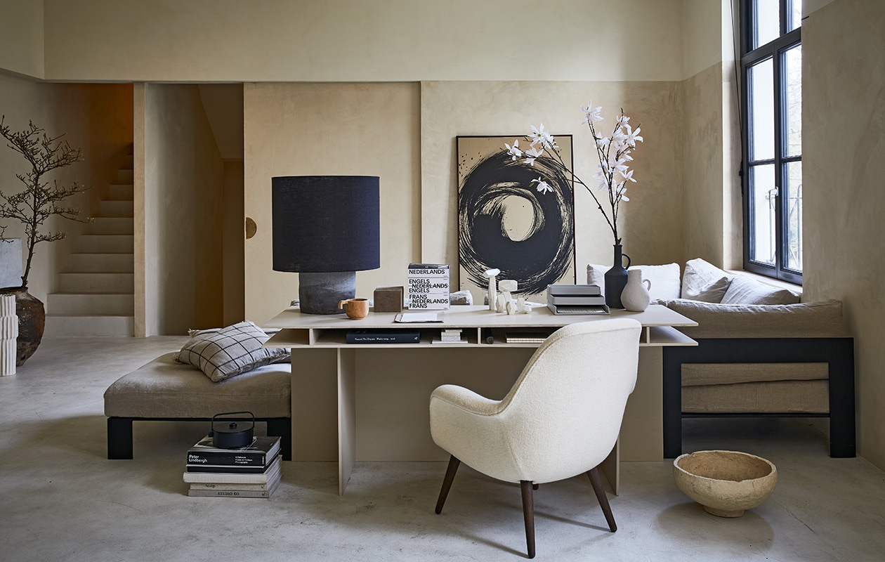 Bureau op maat gemaakt (com-anders.nl). Fauteuil Swoon van Fredericia (designtales.nl). Linnen bank met stalen frame, prijs op aanvraag, lamp met grote kap, papier-maché schaal, muur- en vloer, prijs op aanvraag (anoukb.com). Schilderij, prijs op aanvraag (tessaderijk.com), geruite kussens 50×50 cm (fermliving.com). Grijze organizer Muuto (nordicnew.nl). Witte hoge vaas, zwarte vaas, witte kleine vaas, suède dozenset van 3 (nordal.eu). Zwarte theepot Serax Collage 1,2 l (vtwonen.nl). Overig privébezit.