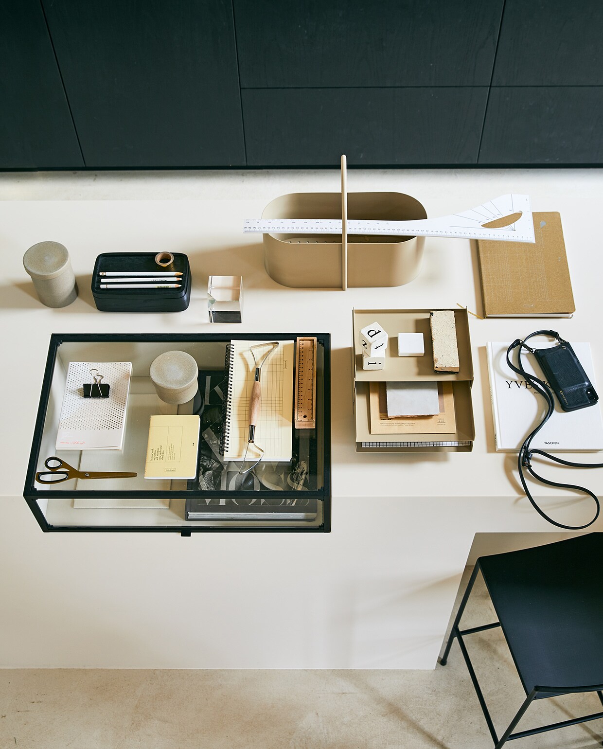 Metalen organizer in kasjmierkleur 22,8×12,7×28,3 cm (bxhxd), metalen toolbox met handvat in kasjmierkleur, keramieken pot met deksel, klein en groot (fermliving.com). zwarte kruk 75 cm hoog, zwarte houten opbergbak met deksel (serax.com). Hay schaar (wonenmetlef.nl). Wit notebook met stippen, klein notebook, desktopplanner met ringband, okergeel notebook A6 Fluorite (tinne-mia.nl). Glazen presse-papier (hm.com). Witte liniaal (jandegrotekleinvakman.nl). Glazen vitrine, prijs op aanvraag (anoukb.com). Overig privébezit.