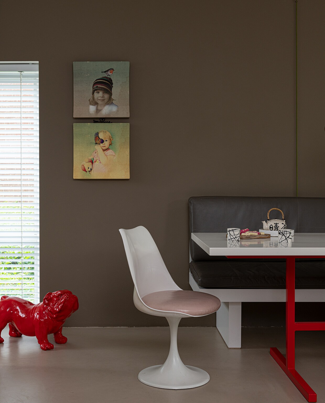 Muurverf Real Grey van Flexa. Schilderijen eigen ontwerp. Bank was een cadeau, de tafel is eigen ontwerp. Stoelen Pastoe. Theepotje kringloopwinkel, marmeren plaatje Sissy-Boy, porseleinen kopjes Henk Wolvers. Rood kunstwerk van hond is een Engelse Bulldog Ceasor.