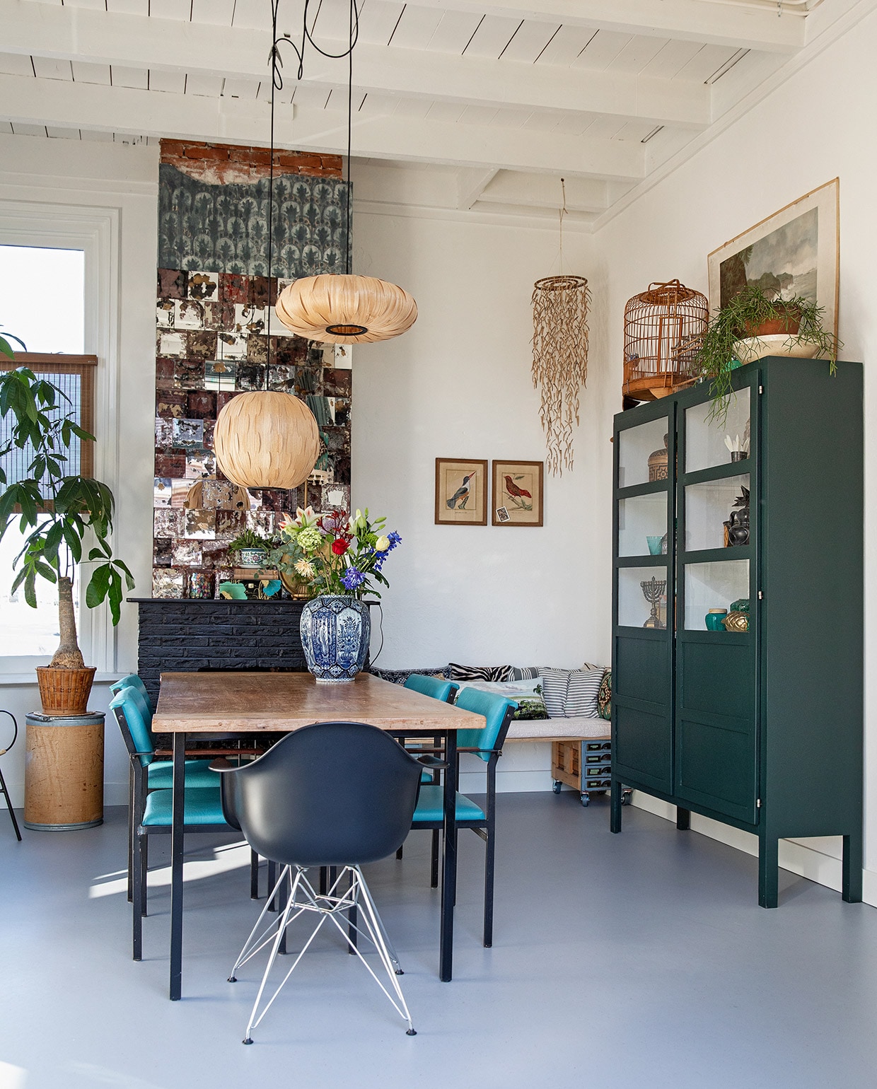 Vloer Marmoleum Cacao in Earl Grey Chocolate via Woontheater de Eclips, ronde kartonnen ton, rieten mand, hangend voorwerp in hoek en etsen aan wand via Bij Lokaal, teakhouten tafelblad vintage met onderstel via Datas, blauwe stoelen Cees Braakman voor Pastoe, zwarte kuipstoel Vitra, hanglampen Dutchbone, Delfts blauwe vaas rommelmarkt, bankje gemaakt van twee vintage archiefkastjes en underlayment, kussens op bank: zebra, verticale streep en horizontale streep gemaakt met vintage stof, landschap Bij Lokaal. Kast zelfontworpen. Op kast: kooi kringloop, witte schaal uit Tsjechië, pot uit Polen, prent achter kast kringloop.
