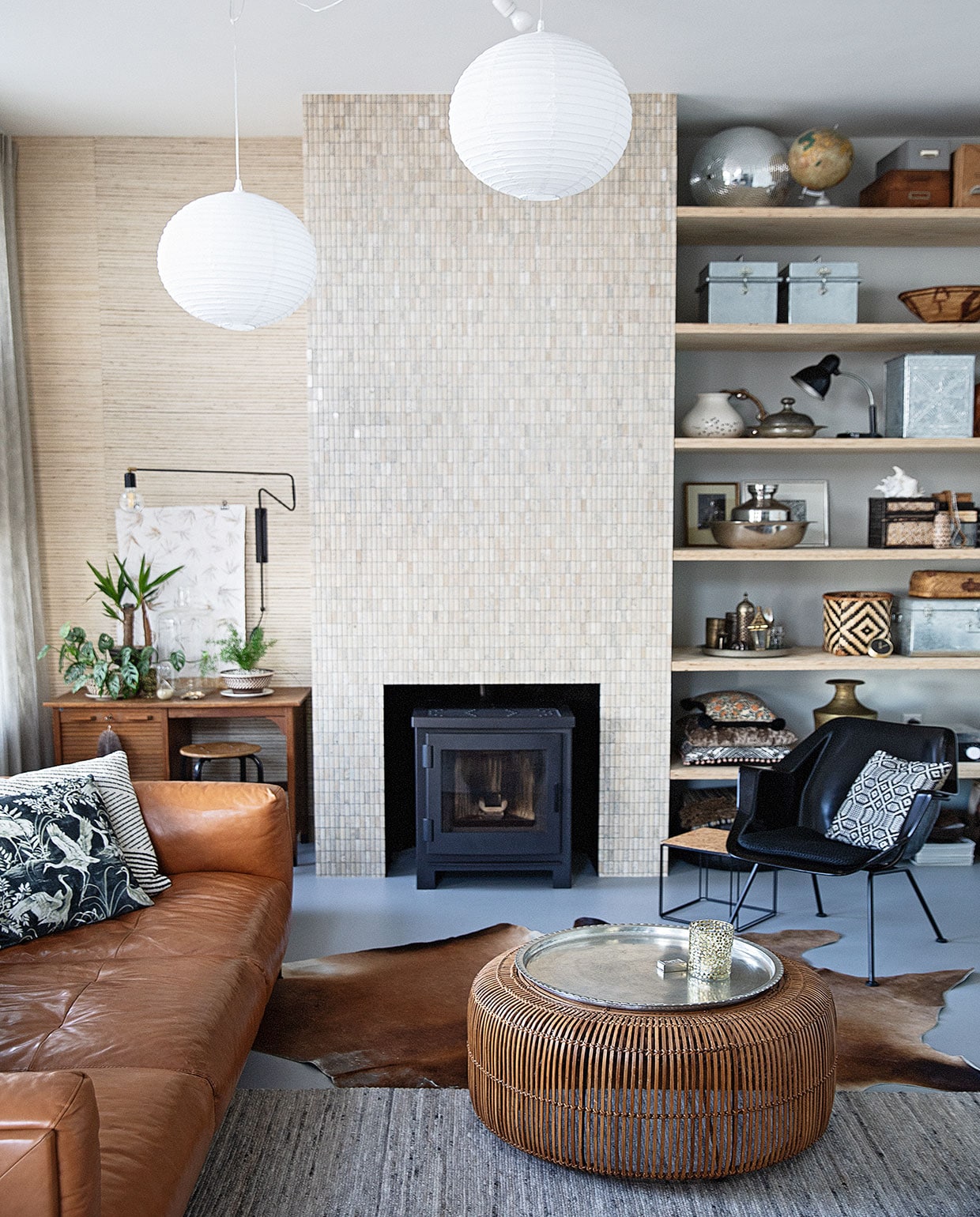 Behang Natural Wall Coverings Eijffinger, tegels natuursteen Praxis, muurverf Papyruswit Ral 8018 Flexa, plafondverf Powerdek Ral 9010 Flexa, planken underlayment. Kachel Arya van Nordic Fire, bureau kringloop Het Goed, zwarte wandlamp House Doctor, zandloper Laif &amp; Nuver, schelp Bij Risje Ameland. Witte lampen Praxis, snoer Snoerboer, bank Het Anker, dierenvel Ikea, vloerkleed Woontheater de Eclips, fauteuil Gispen 416 van Dutch Originals, bijzettafel en kussen vogel zelfgemaakt, kussen strepen Home Delight. Salontafel en waxinelichthouder HKliving, dienblad Ottomania.In kast: vaas met kraanvogels Piet Hein Eek, rotan mand Laif &amp; Nuver, bovenste kussen zelfgemaakt, middelste kussen Kleur op Kleur Interieur, onderste kussen Imbarro, platenspeler Crosley, grote schelp en Matroesjka Bij Lokaal, klok Karwei. Overig vintage of souvenir.