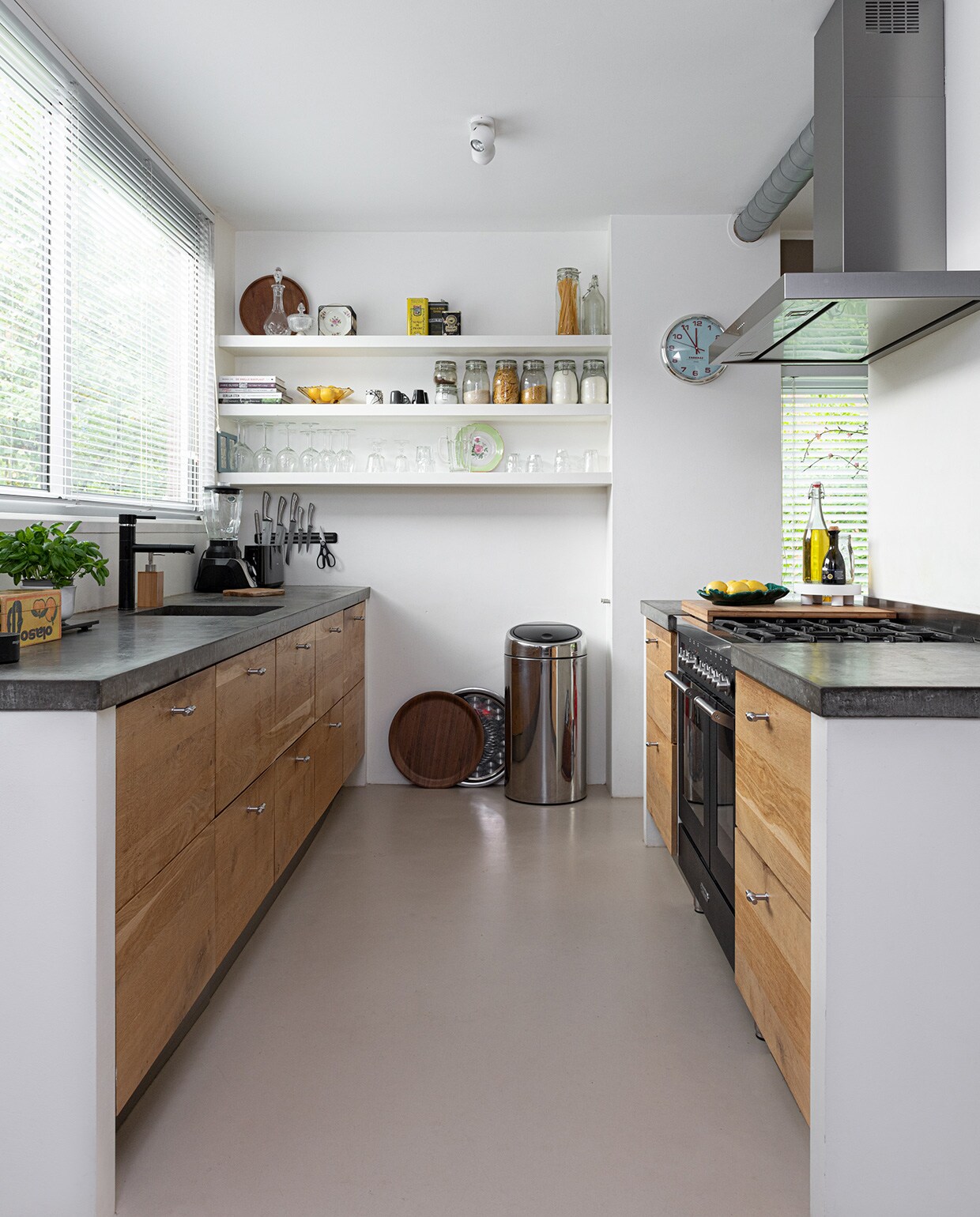 Keuken Ikea, fronten door Koak design, fornuis Fratelli Onofri, afzuigkap Falmec. Marmoleumvloer Walton van Forbo vloeren. Prullenbak Brabantia. Bruin dienblad H&amp;M Home, zilveren dienblad Turkse winkel. Op het aanrecht: snijplank Ikea, fruitschaal vintage. Klok Cabanaz. Op de planken: glaswerk voornamelijk Ikea, dienblad H&amp;M Home. Aan de muur: messenset Berlinger Haus. Blender Bosch. Bakje souvenir uit Mexico.