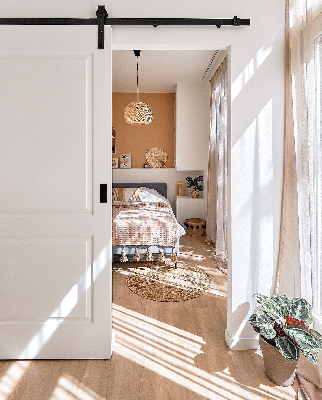Schuifdeur op maat gemaakt. Gordijnen whkmp’sown Wehkamp. Rond vloerkleed Xenos. Bed Ikea. Sprei en kussen Maisons du Monde. Hanglamp Jysk. Muurverf in kleur Piramide van Praxis. Lijstjes gemaakt door een vriendin. Waaier Maisons du Monde. Plantenpot Ikea. Rieten nachtlampje Maisons du Monde. Mand met pompoms H&amp;M Home. Plantenpot vooraan herkomst onbekend.