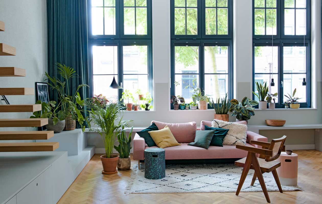 Behang Bazar 219427 van BN Walls. Zwevende eikenhouten trap Decotrap, behandeld met houtolie Monocoat Mist 5%. Ingelijste poster Junique. Vensterbank en kasten op maat gemaakt door Fontijn Interieur Projecten. Hanglampen Malou van Karwei (links) en Mora van Zuiver.Zit-slaapbank Innovation, kussens Karwei en Innovation, wit kussen souvenir uit Marokko. Aardewerken tuinkrukken gebruikt als bijzettafels Made. Stoel Pierre JeanneretOffice Chair via Object Embassy. Kleed Karwei. Planten De Balkonie en Sprinklr, terracotta bloempotten onder andere Sprinklr, Søstrene Grene en H&amp;M Home.
