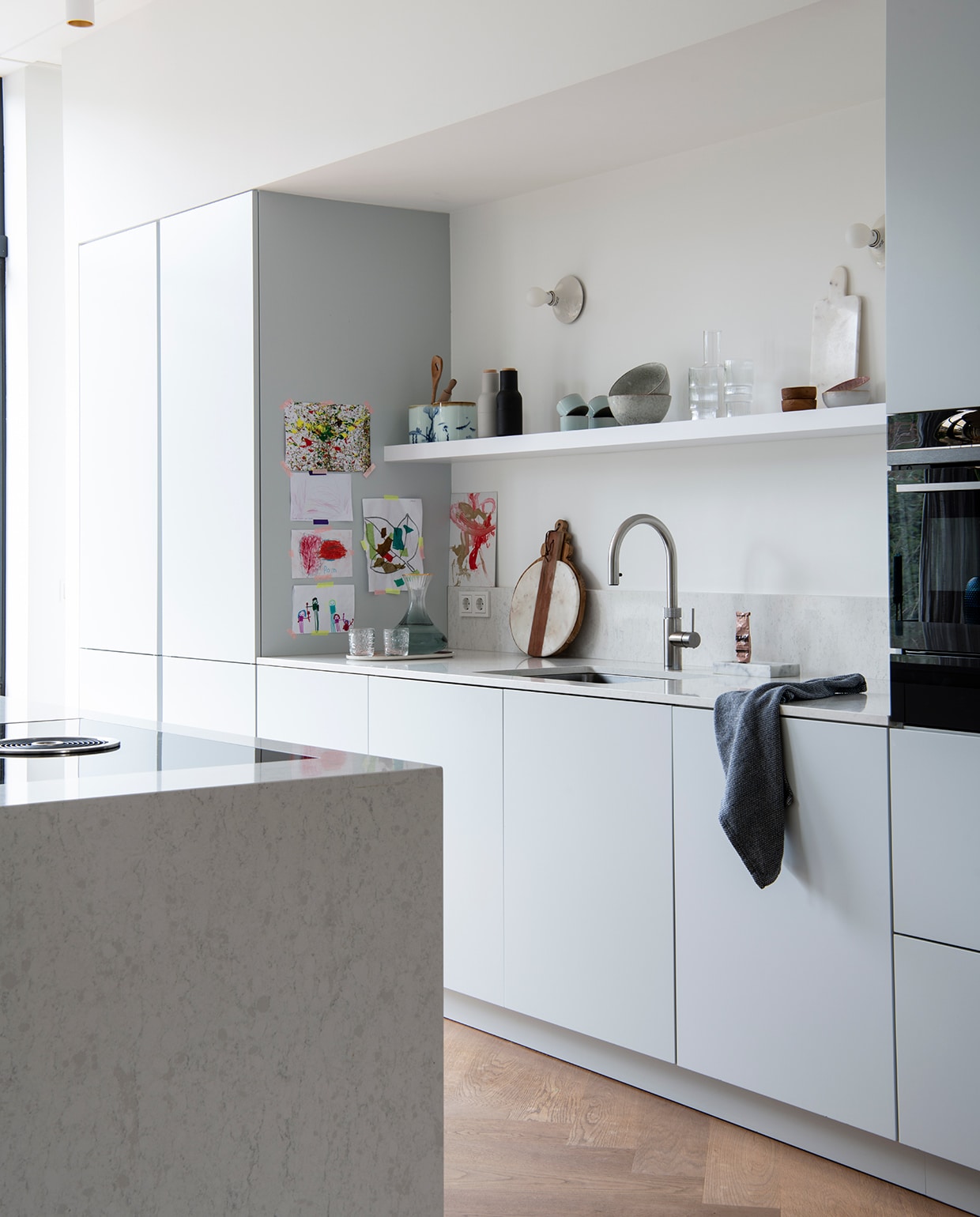 Keuken zelf ontworpen en gemaakt door Keller Keukens. Wandlamp Tom Dixon. Kraan Quooker. Broodplank Pluk Amsterdam. Marmeren zeepschaal en marmeren snijplank Stoned Marble. Theedoek, witte kommen met stipjes en houten kommen Sissy-Boy. Peper- en zoutmolen Menu. Grijze kommen Broste Copenhagen. Fles en glazen Ferm Living.