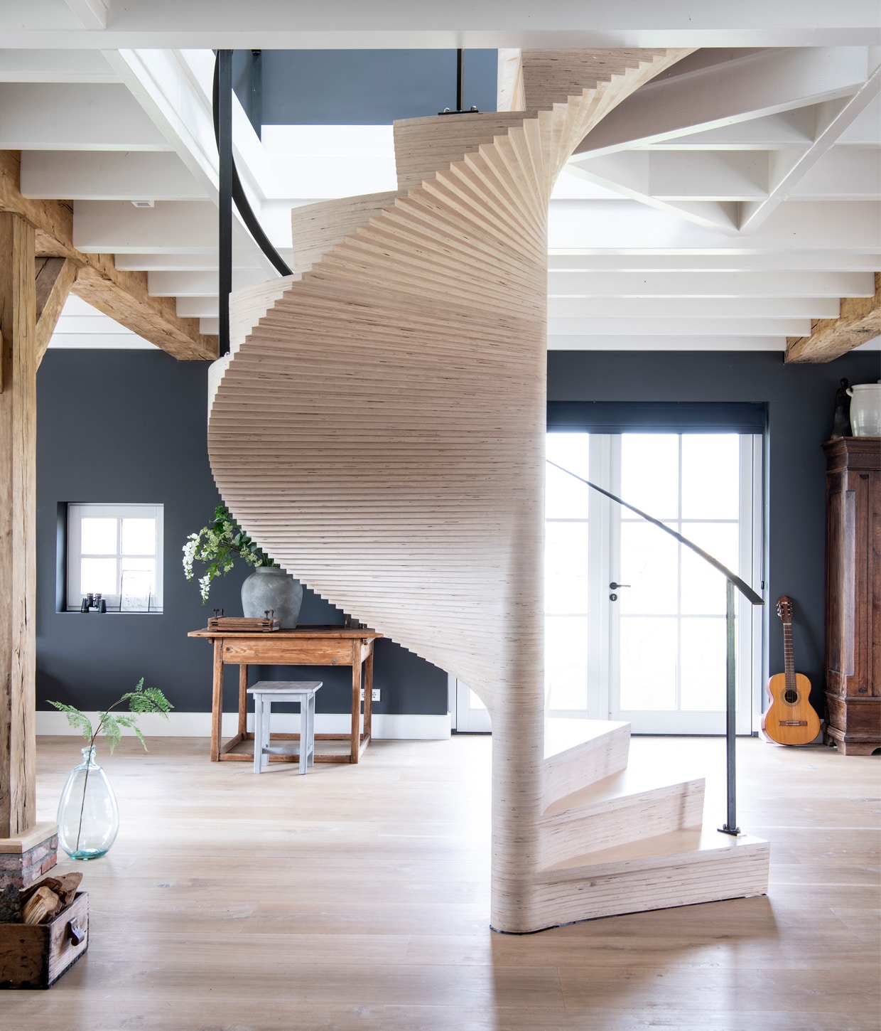 &gt; Licht eiken plankenvloer in drie breedtesDennebos Flooring, trap ontworpen door Buro Loggein samenwerking met Westenwolf Trappen.Balkenconstructie oude onbehandelde eiken balkenFrank Pouwer, vazen Tica, verf op de muur PersianGrey van Painting the Past. Bijzettafel, aardewerkpotten, kist met houtblokken rommelmarkt, gitaarResonata, kruk Stapelgoed, kast antiekwinkel.