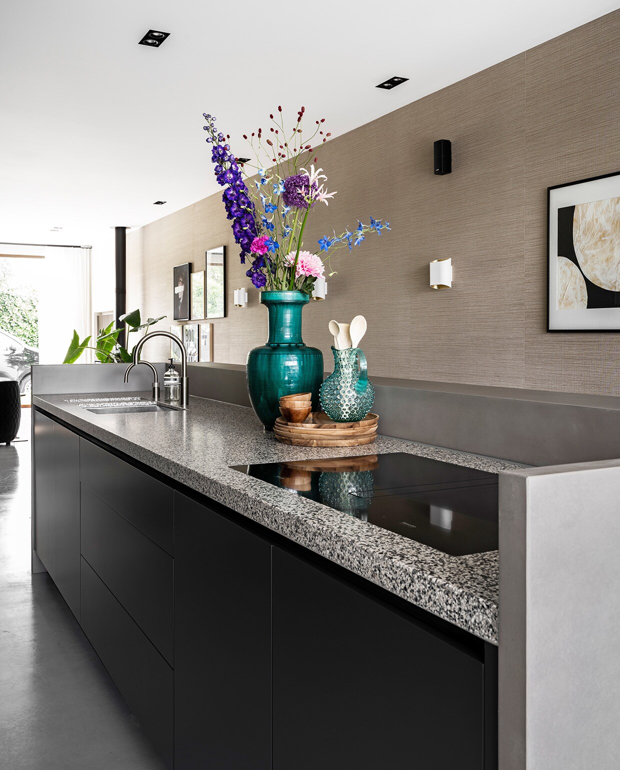 Zelf ontworpen keuken met granieten aanrechtblad en betonnen rand gemaakt door Maek Meubels, apparatuur Miele, blauwgroene vaas en blauwe kan Mischa Hulshof Alkmaar, houten borden en schalen vtwonen collectie, kunstwerk aan muur To the moon and back van Art in Return, witte wandlamp Trapz Modular Lighting Instruments.