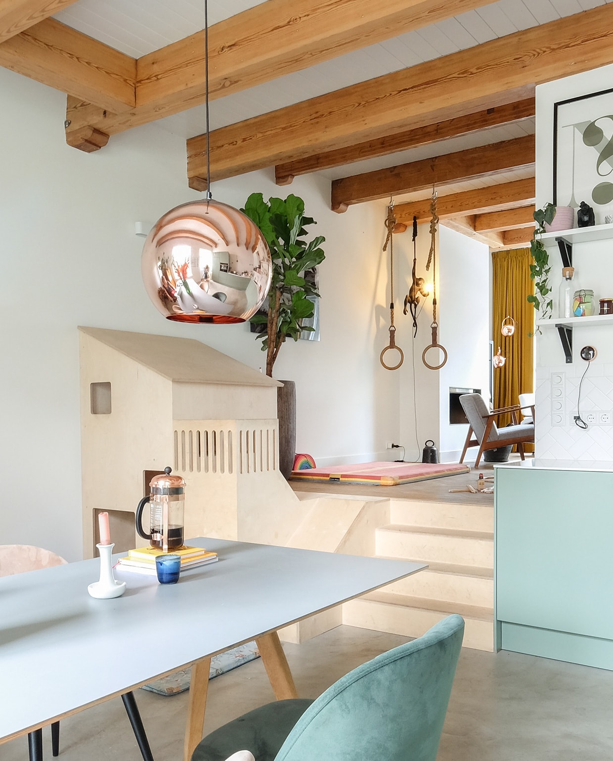 Tafel Hay. Hanglamp Tom Dixon. Herkomst stoelen onbekend. Kandelaar Hay. Cafetière Bodum. Speelhuis gemaakt door Plantvierkant. Speelmat ByAlex Playmats. Mand Ikea. Houten speelgoedvrachtwagen Fagus. Wandlamp Lucide. Gymnastiekringen uit een oude gymzaal. Turnmat Neef Louis. Aaplamp Seletti. Pot met ficus lyrata Intratuin