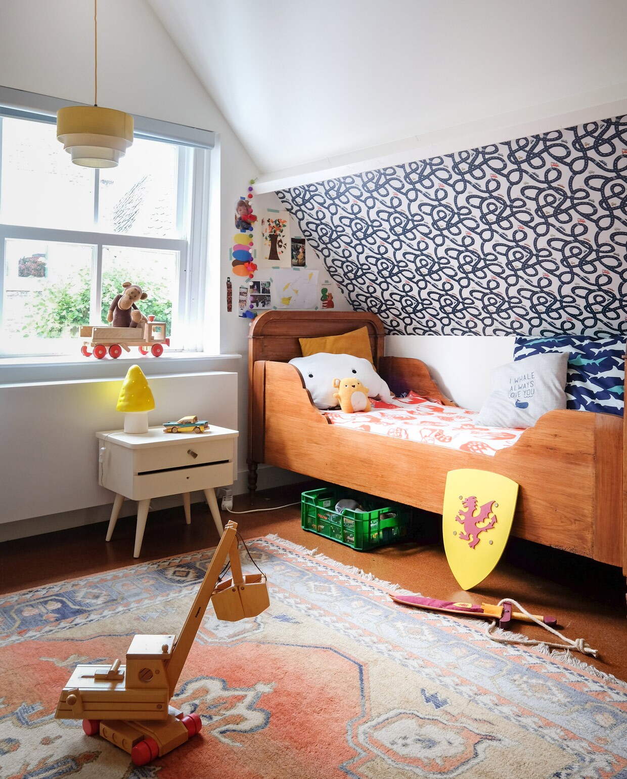 Houten bed en kleed Marktplaats. Houten speelgoed Marktplaats en souvenirs van reizen. Speelgoedkraan Fagus. Behang ByAlex. Kastje vintage. Lamp Heico. Beddengoed Hema. Gele knuffel en kussenknuffel Noofoll, aapje zelfgemaakt. Wapenschild souvenir uit Frankrijk.