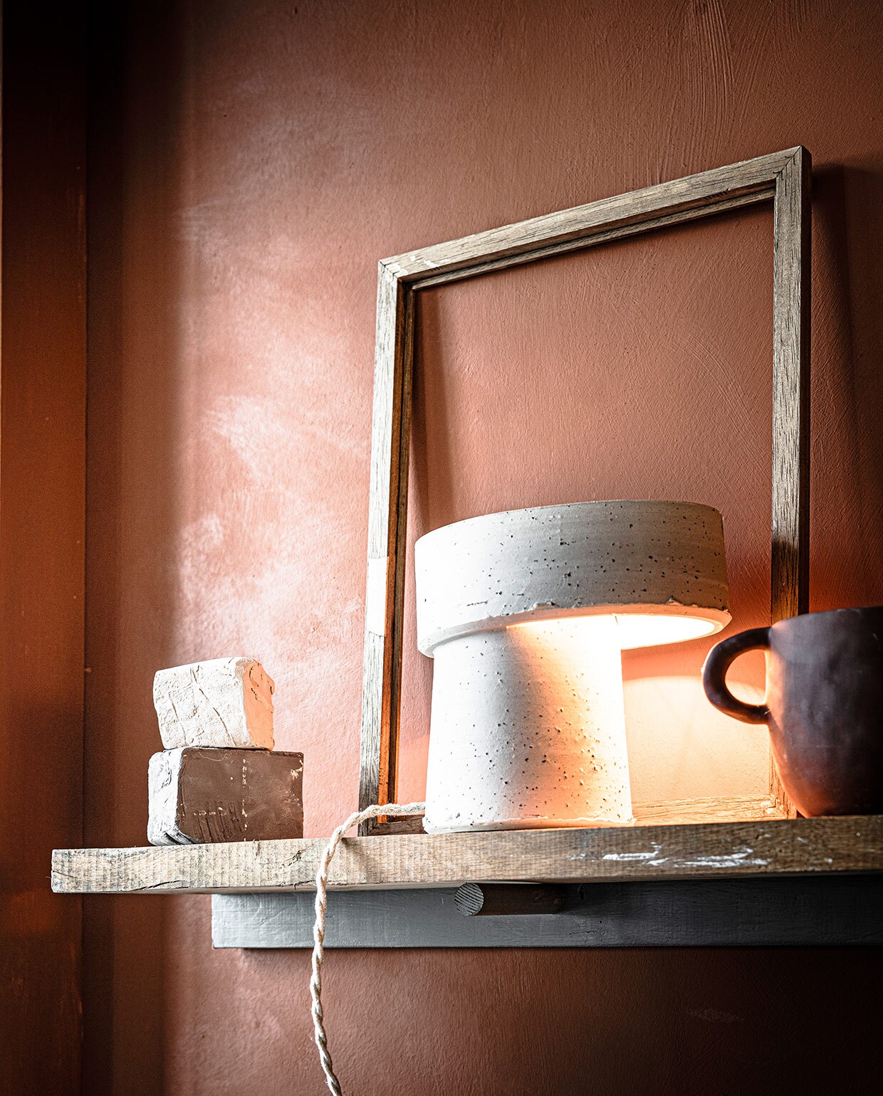 Muurverf Fresco in Terracotta (pure-original.nl). Beige lamp van klei Oysho Table Lamp (studio-yen.com). Vaas Mus Plant Pot (fermliving.com). Stukken klei (artsandcrafts.nl). Oude lijst privébezit.
