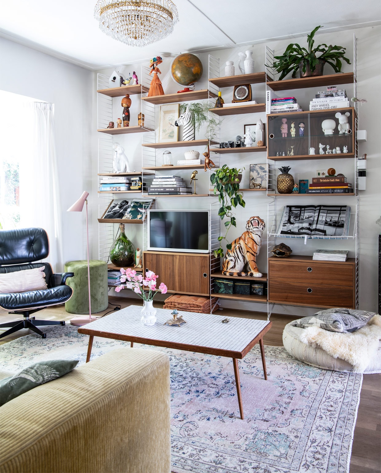 Bank Leolux, kleed Rozenkelim. Eames Lounge Chair en String-kast Co van der Horst. Plafondlamp straatvondst, vloerlamp Kwantum. Groene poef Riverdale, matraskussens Day Home, ecru poef Lodsh. Kussen Livv lifestyle. Tafel en ornament kringloop, kandelaar Sissy-Boy, vaas West Germany. In kast: zebra- en visvaas en lijst met print Sissy-Boy, aap Kay Bojesen, tijger, ornament vogel en klok Dolores del Dia. Tekening Mark van Gennip (mrrk.nl), ananas Zara Home. Overige souvenirs en vintage.
