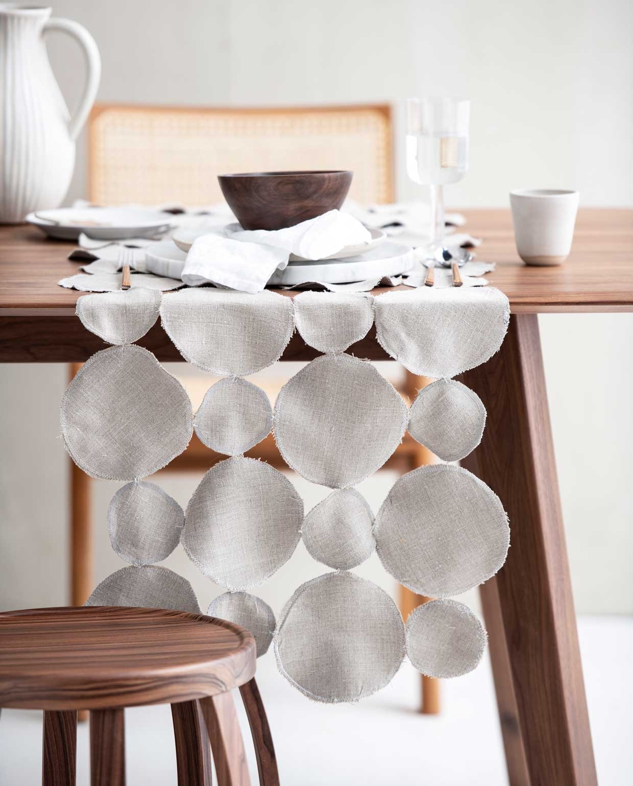 Kruk €1524,-, stoel €2790,-, marmeren onderbord €120,- (edha-interieur.nl). Mok €14,50, wit bord achter €29,-, wit bord op stapel €2,- (sukha.nl). Tafel €1149,- (demachinekamer.nl). Houten kom €17,99, wijnglas €5,99, bestek vanaf €1,99, witte kan €35,99, (zarahome.com). Wit linnen servet €9,99, (hm.com). Lepel privébezit.