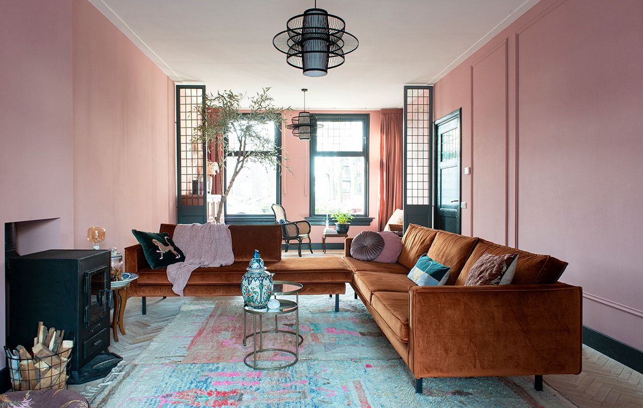 Muurverf Hellebore 275 van Little Greene. Banken BePureHome. Kussen met print Sissy-Boy. Velvet kussen Jysk, roze kussen Kwantum, plaid H&amp;M Home. Vloerkleden gekocht in Marrakech. Bijzettafel en Delfts blauwe schaal familiestukken. Glazen pot en vaas met deksel gekregen. Tafels en gouden waxinelichthouder Action, onderzetters gekocht op Rhodos. Waxinelichthouder kringloopwinkel.