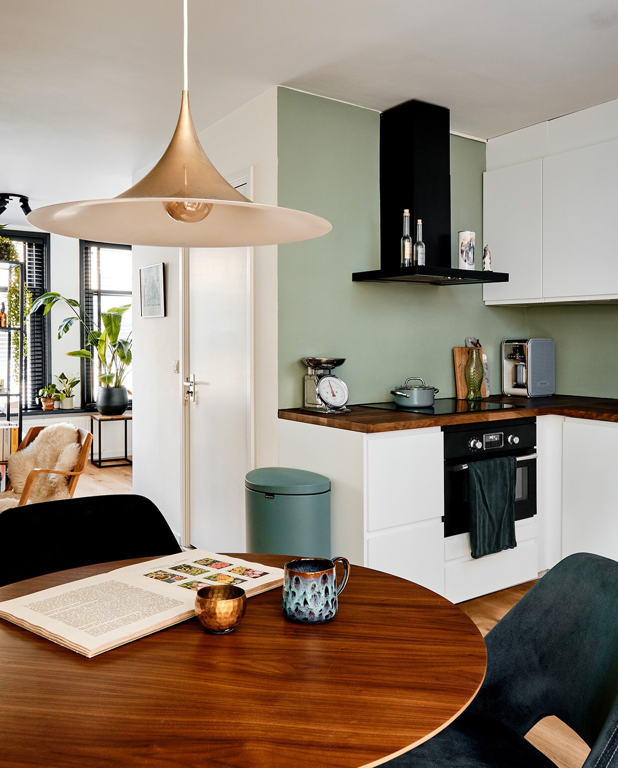Eettafel en stoelen Loods 5, theepot Arzberg, mok kringloop. Stoel tweedehands. Plafondlamp, schapenvacht , vakkenkast en keuken Ikea. Prullenbak Brabantia, weegschaal kringloop, pan De Padova. Herkomst marmeren snijplank onbekend, houten snijplank The Maker Store. Handdoek Hema, flesjes en kaars Mondo Mediterraneo.