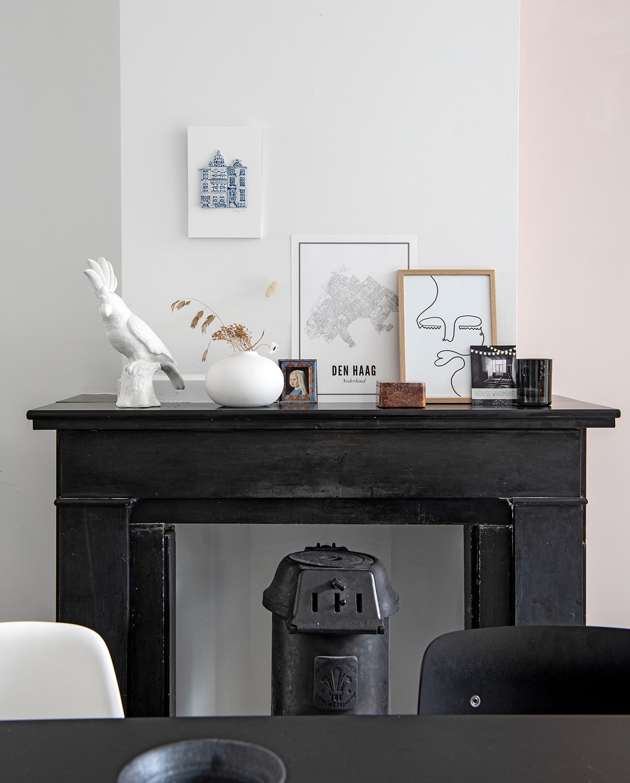 Open haard en gietijzeren kachel zaten al in het huis. Kaketoe Pols Potten. Vaas Urban Nature Culture. Print huizen Alexandra Breeze Ceramics, kaart van Wijck, print gezichten Studio Lisa. Antieke houten doosje vintage, foto van een schilderij dat Britts tante van haar maakte.
