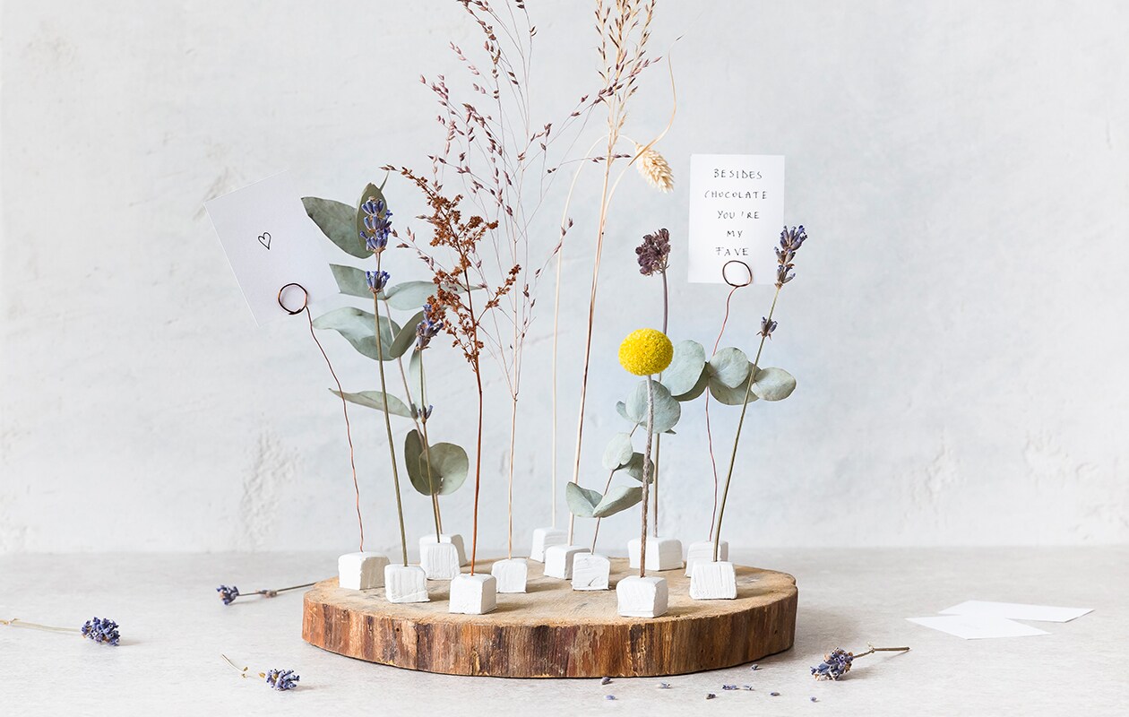 Houtschijf Paulownia Ø 25 cm € 4,25 (decoratietakken.nl). Witte boetseerklei Fimo Air, 500 g € 2,49 (ava.be). Koperdraad 0,50 mm, per 50 m € 3,25 (boerma.nl). Witte kaarten, per 100 € 14,90 (bol.com).