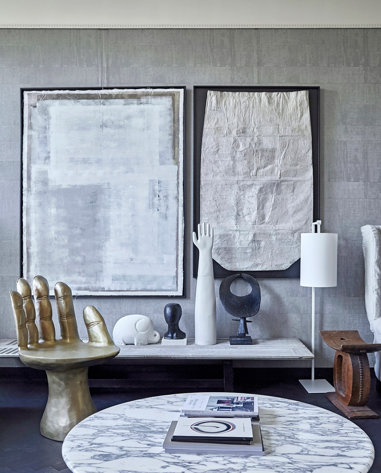 Behang Atelier d’Artiste Elitis via Loggere Wilpower. Gouden stoel/hand Pols Potten, stalamp Serge Mouille. Tafel antiek luik met los vintage onderstel. Witte olifant en witte hand vintage via it Flinkeboskje, overige vintage accessoires en Japanse vintage rijstzak in zwarte baklijst via Nrdrhvn91. Zwart Object Ming Stylemeister. Schilderij Laura de Wilde. Tafel op voorgrond Knoll.