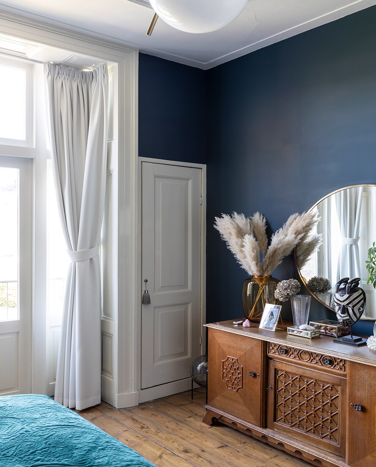 Muurverf Hague Blue Farrow &amp; Ball, originele vloer uit 1889, hanglamp Flos, bed Auping, nepplant Strelitzia en pot Jasmijn Bloembinders, wandlamp Karwei, blauwe vaas HKliving, vogel Toikka Iittala, fotolijst van Christians ouders geweest, beddengoed bloemenprint, wollen plaid, paars kussen en rond kussen Essenza.