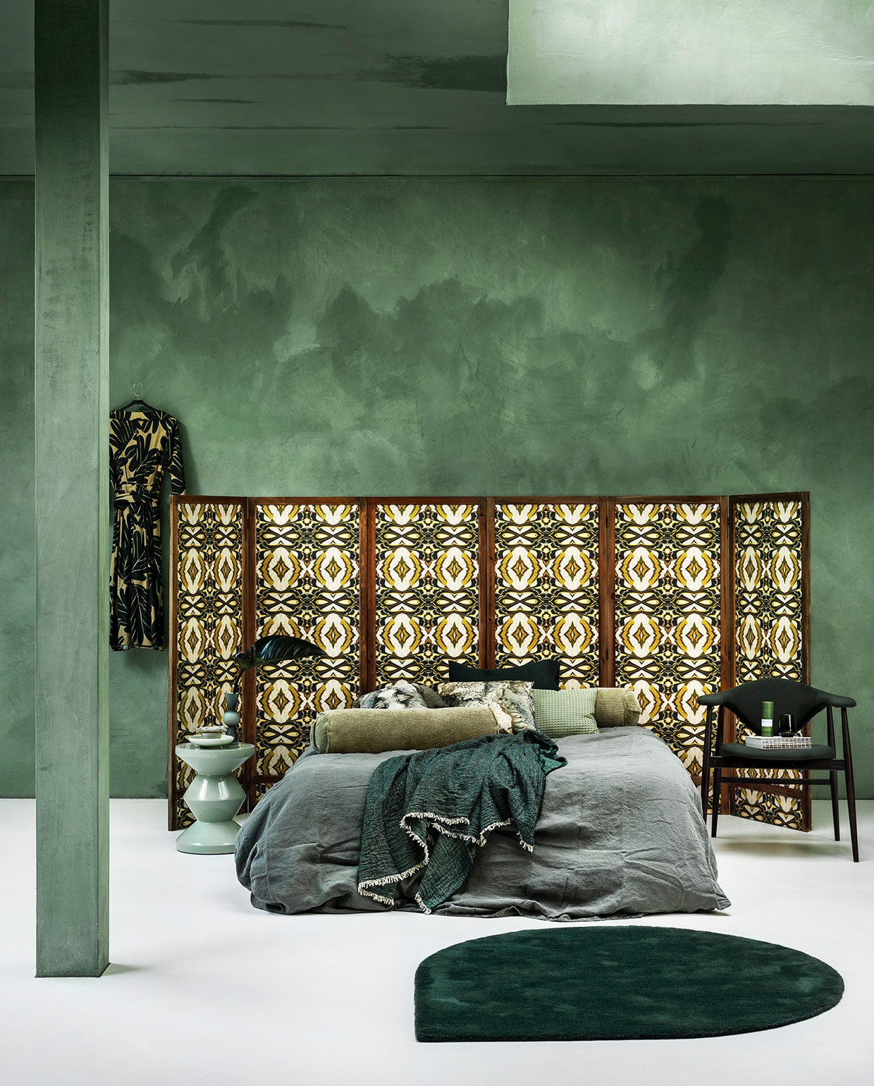 Panelen prijs op aanvraag (com-anders.nl) met daarop behang Casca Belle van Hanneke van de Pol, per rol € 99,95 (artwallcollection.com). Linnen dekbedovertrek, 240×220 cm € 149,95, groene plaid € 99,95, wafelstoffen kussen € 14,95 (vandyckshop.nl). Rolkussen € 32,95 (hkliving.nl). Kussens met dessin van Chantal Keizer € 89,95 (est1966.nl). Mintgroene bijzettafel € 245,- (polspotten.nl). Stoel Masculo van Menu € 1200,-, druppelvormig vloerkleed Stilla van Aytm € 399,- (goeds.nl). Vaas van Design House Stockholm € 42,20 (vtwonen.nl). Kom € 28,- met salie € 8,50, groene koker met matcha Whisk Antwerp € 24,99 (thewhitedoorstudio.nl). Groen glas per 2 € 64,90 (iittala.com). Jurk (natan.be). Kalkverf Lagune, per liter € 48,- (cartecolori-dialma.nl).