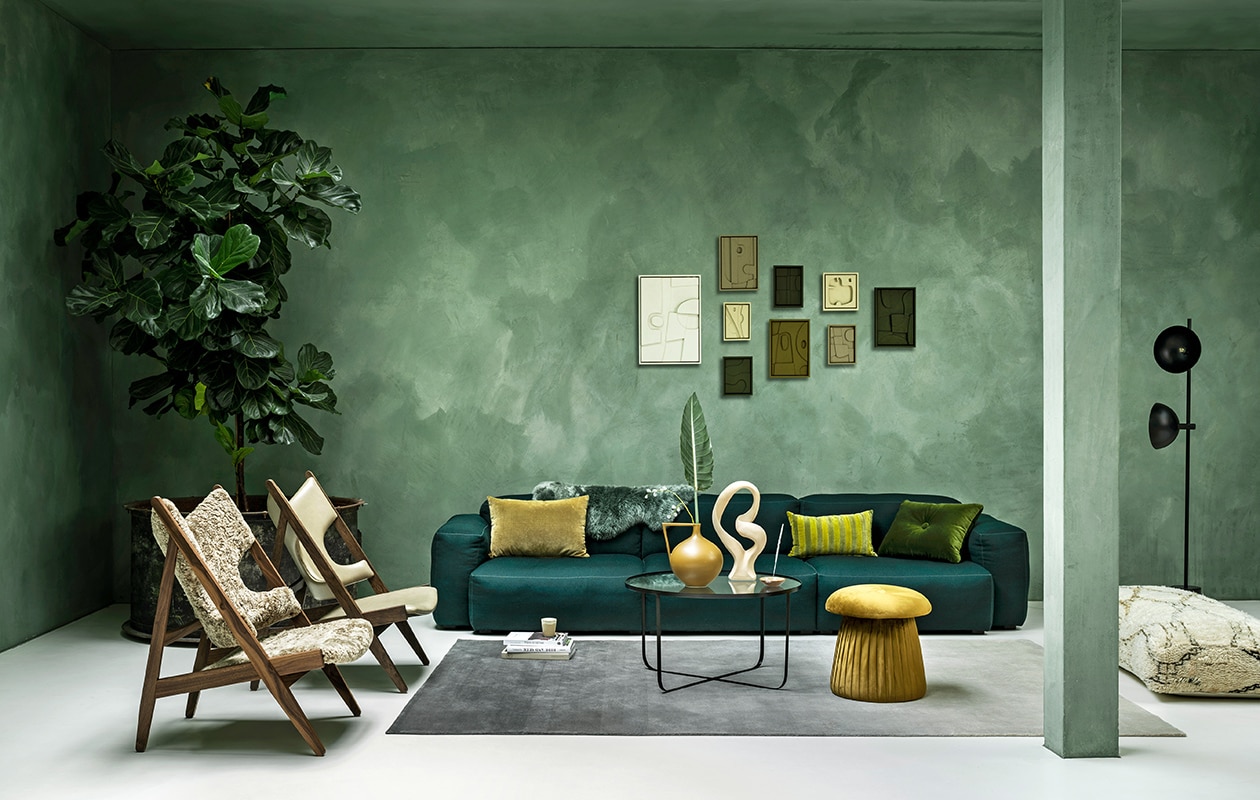 Wollen elementenbank van Hay, 74,6×95,5 cm (dxb), per element vanaf € 2129,-, schapenvacht € 69,- (eijerkamp.nl). Vloerkleed 200×300 cm, per m2, € 900,-, leren Knitting stoel van Menu vanaf € 2595,- (kasstoor.nl). Schapenwollen Knitting stoel van Menu vanaf € 2595,- (). Salontafel van glas en staal van Bloomingville € 269,-, velours poef van Bloomingville € 111,20, mosgroen velours kussen van Hay € 79,-, vaas van HKliving € 99,90, wit object van Bloomingville € 34,20 (vtwonen.nl). Berber zitpoef € 319,- (elramlahamra.nl). Metalen vloerlamp Handvark € 585,- (goeds.nl). Kunst aan de muur van Edith Beurskens vanaf € 130,- (). Okergeel velours kussen € 29,95, gestreept velours kussen € 32,95, zandkleurige beker € 6,- (hkliving.nl). Waxinelichthouder € 39,-, wierook € 20,- (sukha.nl). Kalkverf Lagune, per liter € 48,- (cartecolori-dialma.nl). Overig privébezit.