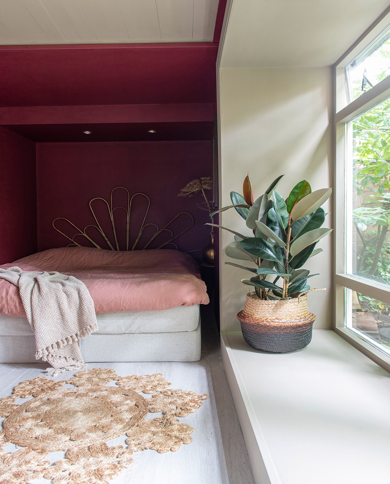 Muurverf en lakverf  van Farrow &amp; Ball. Bed . Achterwand zelfgemaakt van bamboe plantensteunen. Kussen en plaid  Mand , erin een rubberplant. Laminaatvloer restpartij van een winkel die niet meer bestaat. Vloerkleed garage sale. Bijzettafel , herkomst pot onbekend, tak gedroogde berenklauw.