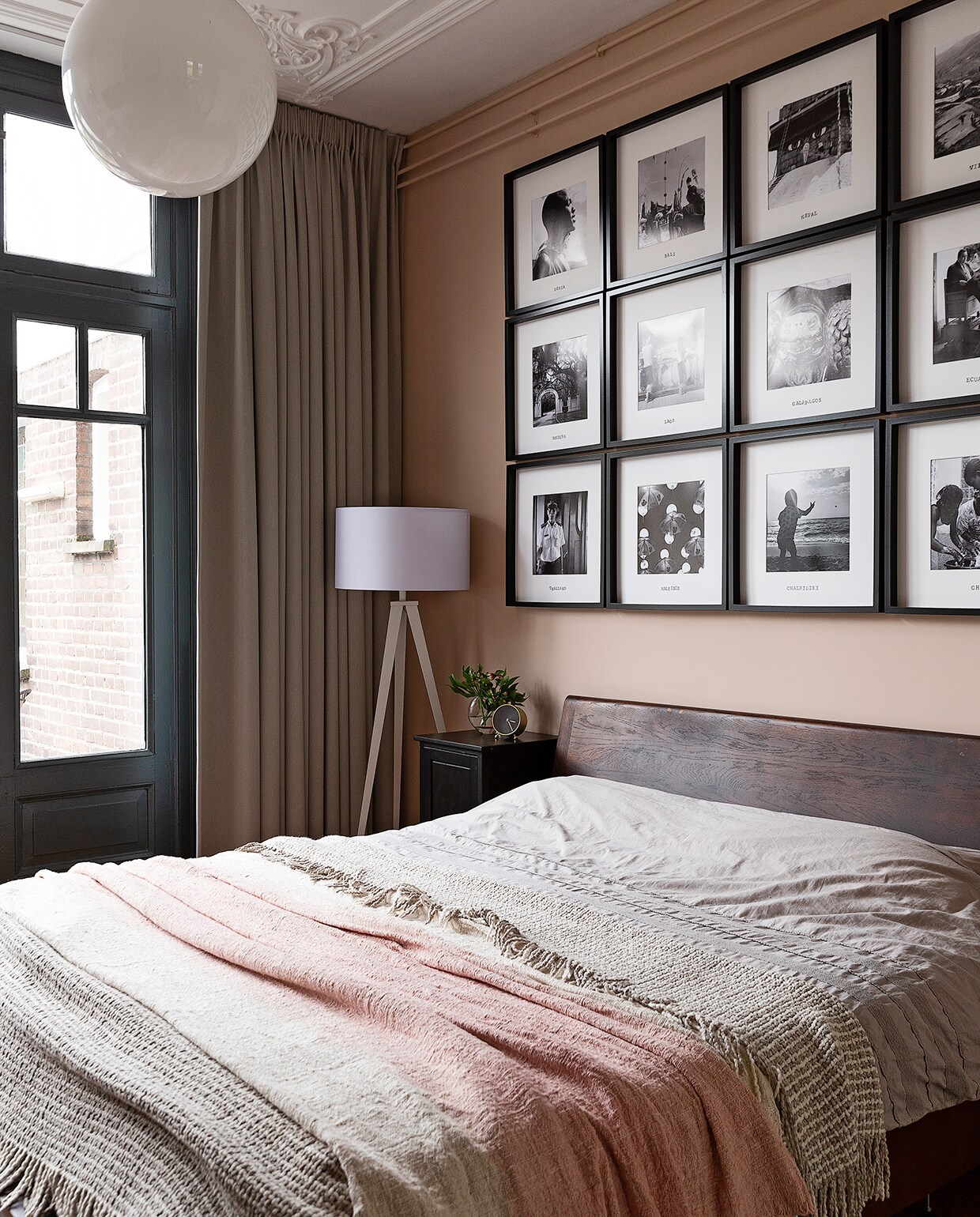 Op de wand boven het bed foto’s van alle verre reizen die Merijn en Stan hebben gemaakt. Lijsten Ikea. Bed Goossens. Vloerlamp Zuiver. Roze sprei Loods 5. De beige sprei kochten ze tijdens hun huwelijksreis in Ecuador.
