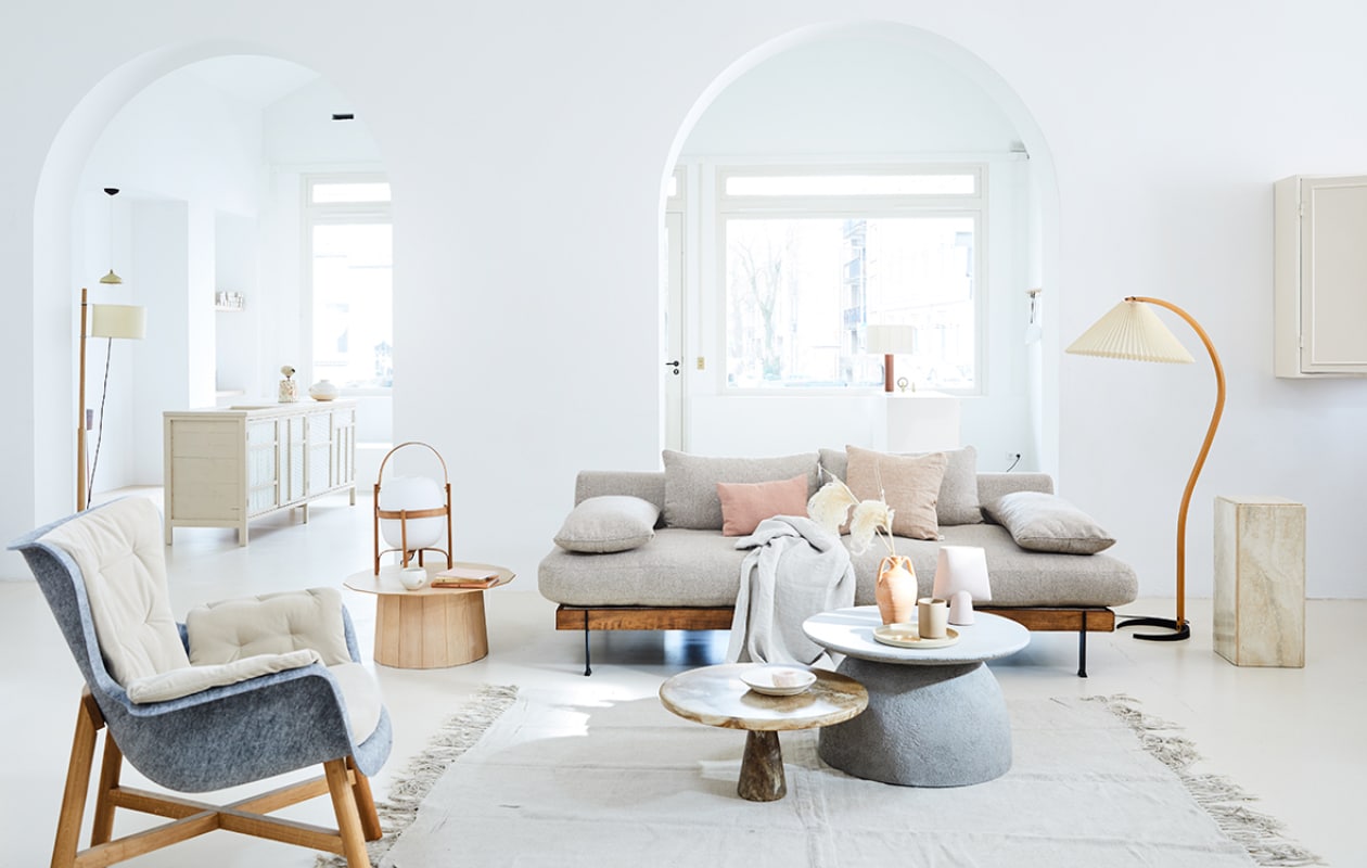Staande lamp links van Santa &amp; Cole, pilaar Travertin Vintage, staande vintage lamp, beker van Hasami Porcelain, bord van Hasami Porcelain, messing schoteltje, diep bord van keramiek van Takashi Sogo, salontafel links van Karimoku New Standard, tafellamp van Santa &amp; Cole, schaaltje van keramiek Takashi Sogo (pantoufle-design.nl). Bank exclusief stof van l’Authentique (viavia-gorssel.nl). Betonlook bijzettafel (casagitane.com). Lage bijzettafel van gerecycled plastic van Dirk Vander Kooij (frozenfountain.nl). Roze handgemaakte vaas van keramiek (101cph.com). Marmeren bakje (stonedmarble.com). Linnen vloerkleed van HK Living (vtwonen.nl). Grijze fauteuil van gerecyclede petflessenflessen (demachinekamer.nl). Kussens Pink Salt van biologisch linnen, linnen plaid (bymölle.com). Kruikvaas en boeken privébezit.