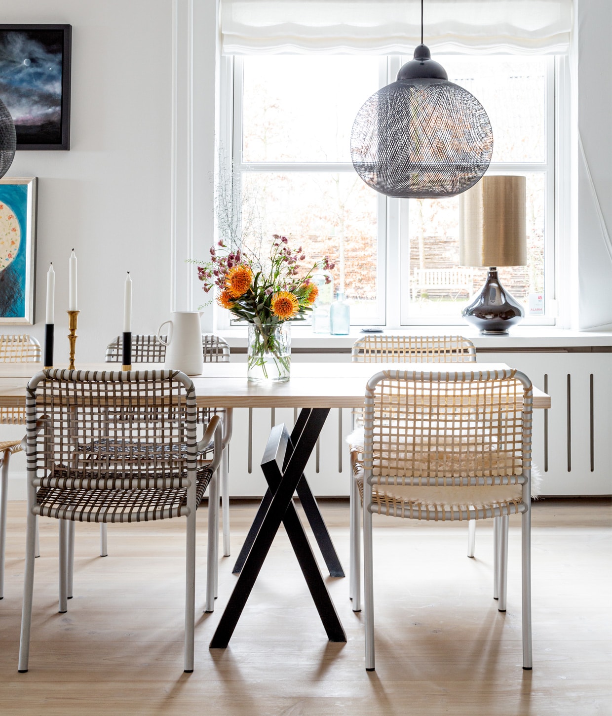 Muurverf Strong White van Farrow &amp; Ball. Tafel en zwart servies zelfgemaakt. Stoelen Casa Shop. Kan Louisiana Museum of Modern Art. Kandelaars erfstuk. Hanglamp Moooi. Tafellamp Rue Verte. Schilderij Kurt Trampedach.