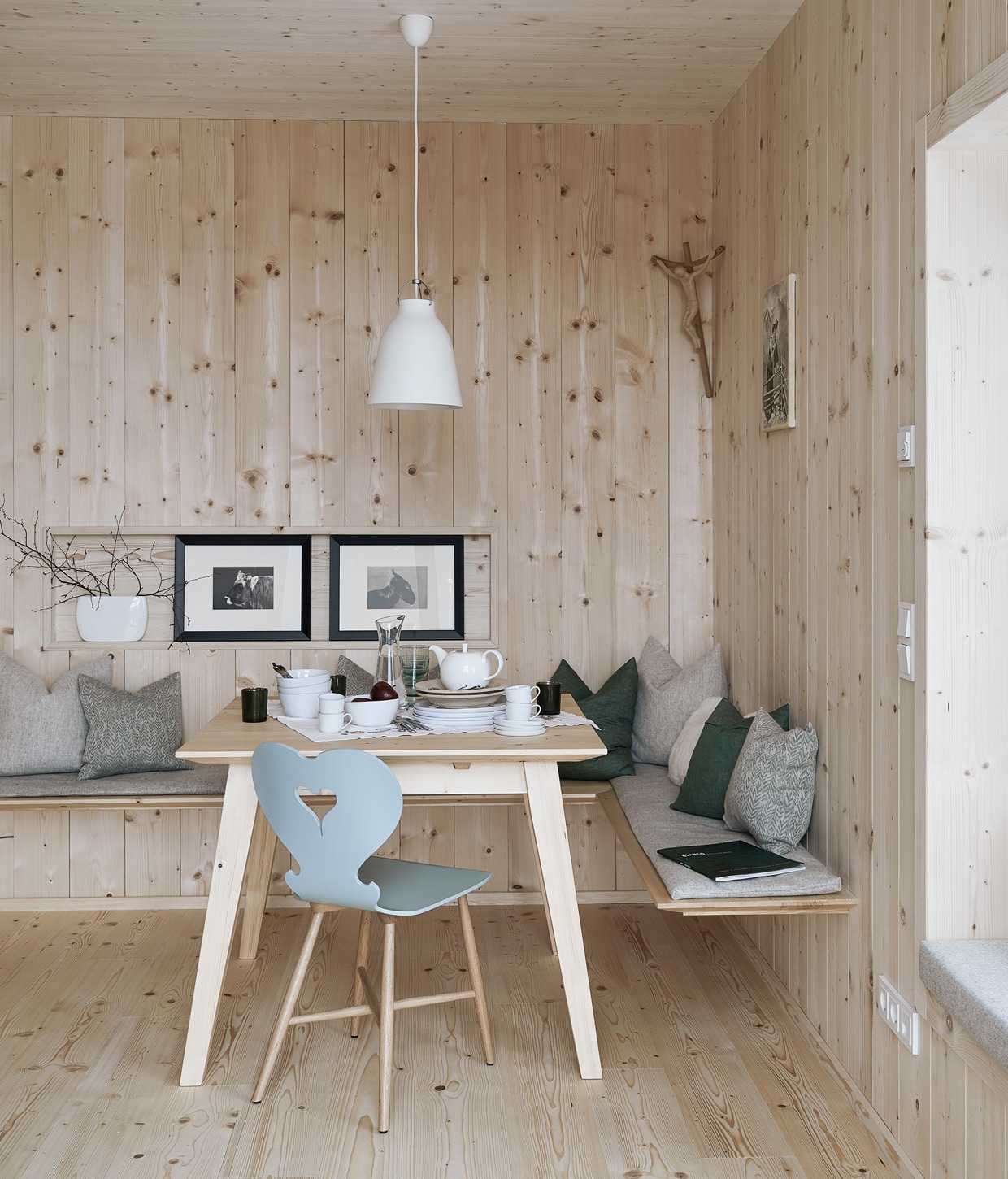 Vurenhouten wandbekleding en vloer. Tafel op maat gemaakt door een lokale timmerman, stoel Trix van Schmidinger Möbelbau. Linnen kussens van Leitner Leinen, wollen kussens van Loden Steiner. Servies Piana van Lambert, hanglamp Caravaggio van Fritz Hansen, ingelijste prints uit een kalender. Herkomst overige items onbekend
