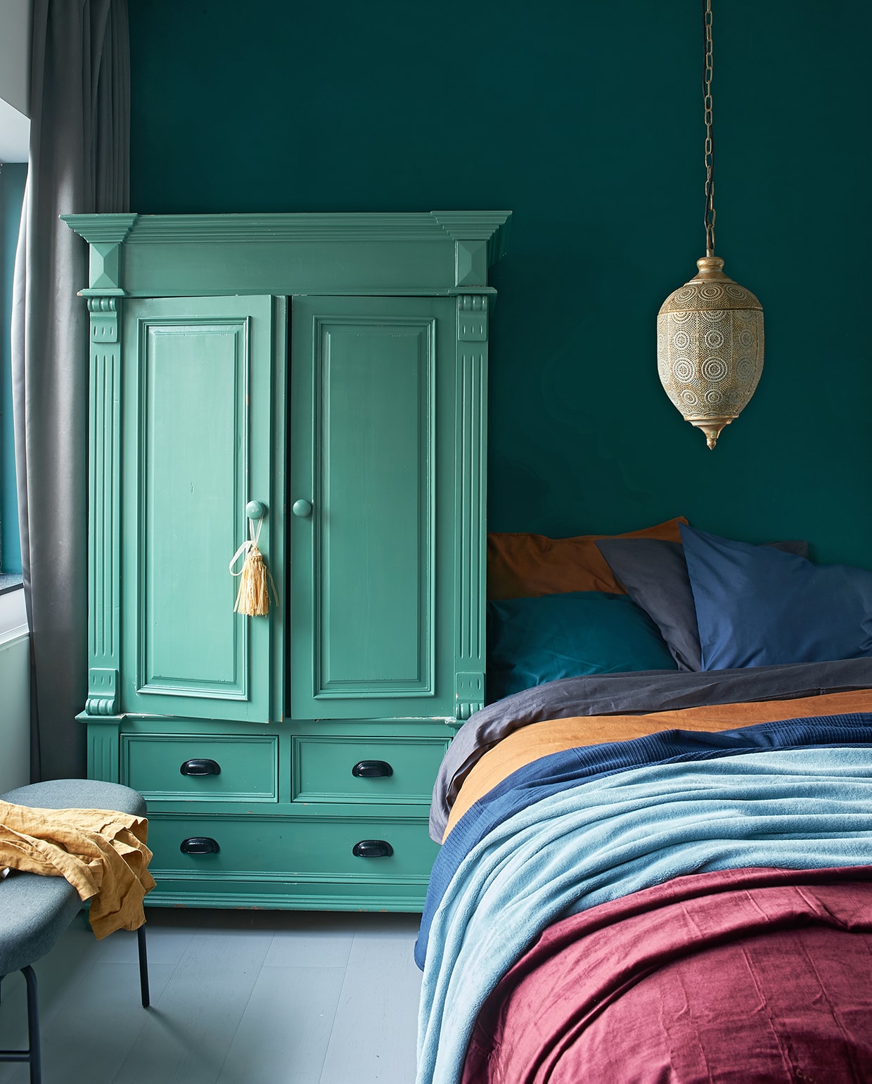 Kleur op wand Absolute Matt Emulsion (littlegreen.nl). Kast in kleur Marine Blue, matte lak, per liter (littlegreen.nl). HanglampMaysa. Grijsblauw dekbedovertrek Puderviva, 200×200 cm, donkerblauwesprei Indira, 250×150 cm (lxb), lichtblauwe sprei Trattviva, 230×250 cm (lxb), groen kussenovertrekSanela, 40×65 cm (lxb) (ikea.nl). Geel katoenen dekbedovertrek200x220 cm, tafelkleed van gewassen linnen (op bankje), 145×250 cm (lxb), donkerrode sprei (hm.com). Bankje Aalborg.