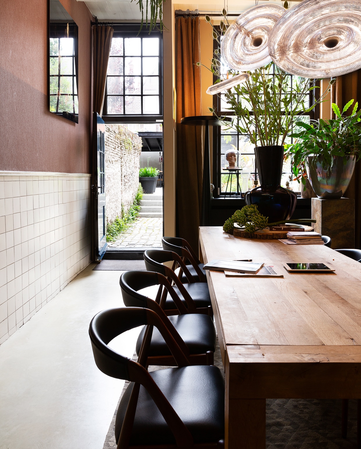 Overal in het huis zijn de handgemaakte potten van Ecri te vinden. Toen Gerwin nog in Italië woonde, had hij in Verona zijn eigen bloemenzaak, waar hij potten van dit merk verkocht. Tafel van Linteloo. De stoelen zijn vintage, en liet Dennis overkomen uit Denemarken. De zwarte designlamp van Prandina kocht Dennis voor een kopje op marktplaats.nl. Vloerkleed uit Alexandrium.