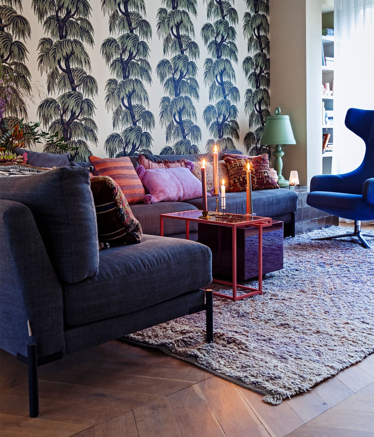 Behang Babylon van House of Hackney, vloer eikenhouten Hongaarse punt via De Oude Plank, vloerkleed Beni M’guild van World of Blends, bank Sleeve 3-zits en Sleeve loveseat vtwonen, fauteuil Grand Repos Vitra, bijzettafel roze prototype van Ontwerpduo gekocht tijdens Dutch Design Week, bijzettafel paars Mirror Block Table HKliving, kaarsen Sissy-Boy, kandelaars Household Hardware en Sissy-Boy, groene tafellamp Paper Moooi, kleine lamp waxine oudelampentafellichtje Piet Hein Eek, kussens vintage berber The Souks.