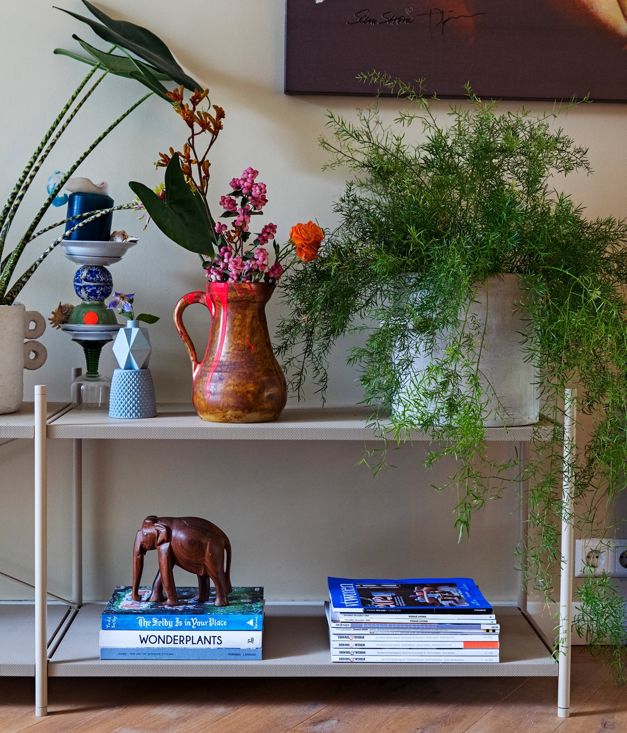 Muurverf Little Green, kast Punctual in Cashmere Ferm Living, vaas twee oren Earth en betonnen bloempot Serax, kandelaar oud servies en kan met fluo roze vlek van vazenvanjanssen, op elkaar gestapelde blauwe vazen Lenneke Wispelwey, schilderij Jörg Döring, olifant vintage.