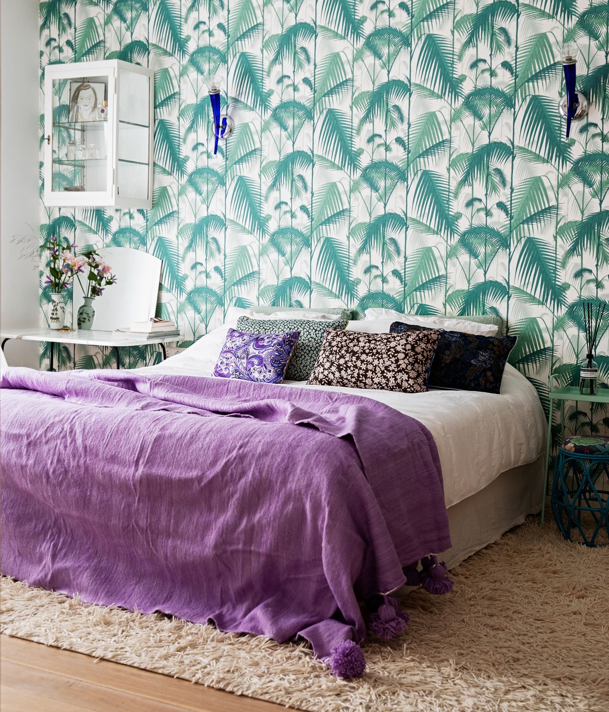Behang Palm Jungle F111/2005 Cole &amp; Son, bed boxpring Eastborn, wandlampen gekregen van Nicolettes ouders, handgemaakte berber pompomdeken The Souks, wit beddengoed Four Leaves, vloerkleed Ikea, kussens Doris voor HKliving, vloer whitewashed eikenvloer De Oude Plank, groen tafeltje Loods 5, krukje Rice vintage, geurstokjes Marie-Stella-Maris.