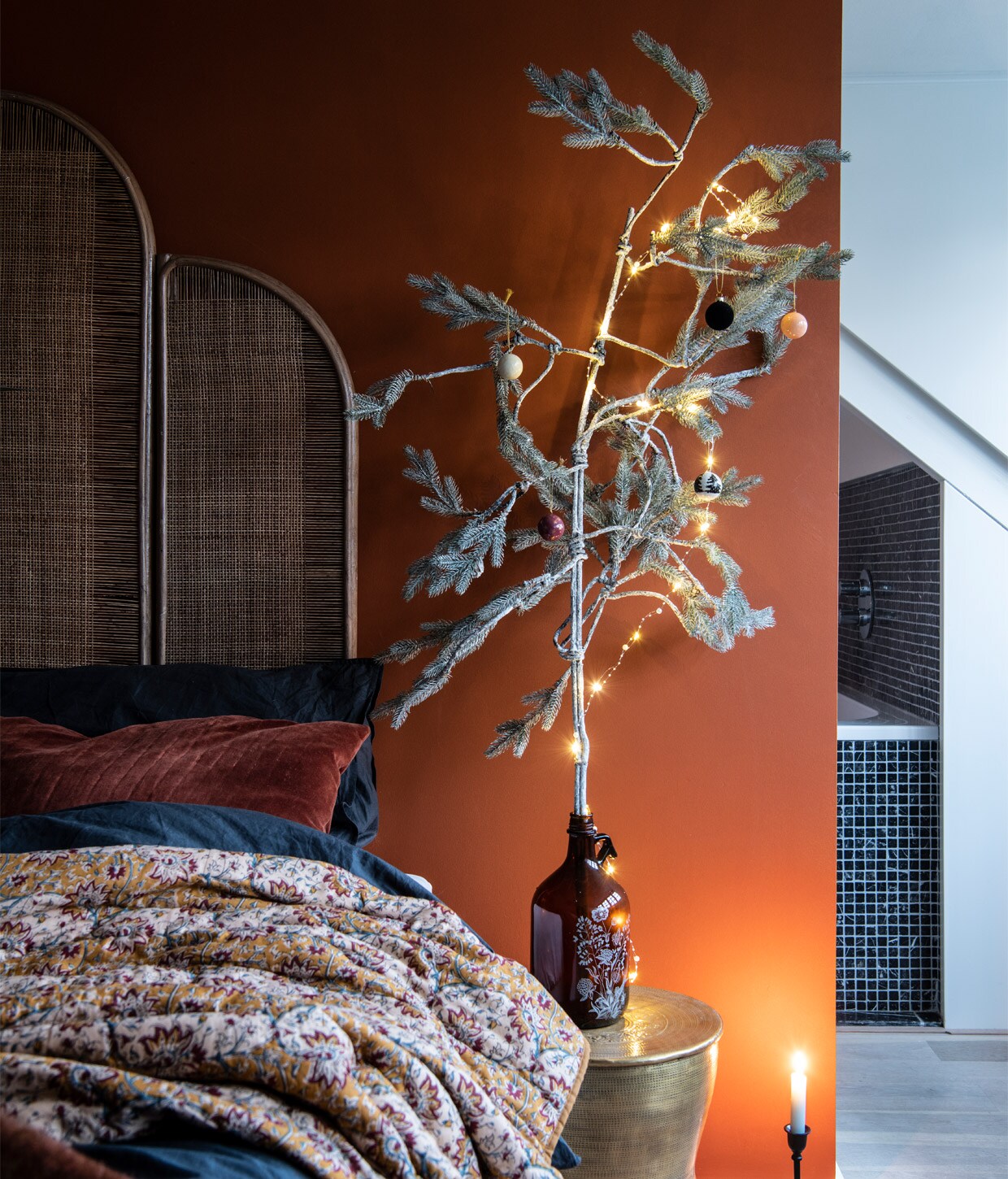 Muurverf Roest van Praxis. Bed Ikea. Nachtkastje, lamp, kussens, gouden kruk en vacht Madam Stoltz. Kamerscherm als headboard en plaid Nordal. Papieren sterren Delight Department. Beddengoed H&amp;M Home. Vaas vintage.