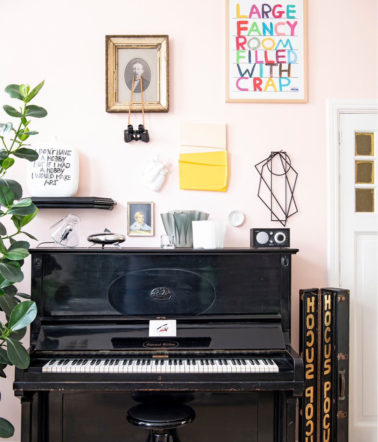 Op piano: lamp Bye bye van Menno Dieperink, bonbonnière Peyrano van Alessi, grijze vaas Cartoccio van FontanaArte, witte vaas Savoy van IIttala, radio Tivoli Audio, metalen plaatje Helicopter crash van Job van den Berg. Aan de muur: hartvaas Love in bloom van Seletti, geel kunstwerk Nearly van Jochem Rotteveel, kunstwerk gekleurde letters David Shrigley, zwart object Trivets Muller Van Severen, wit bordje Thomas Eyck. Overige kunst gemaakt door Birgit.