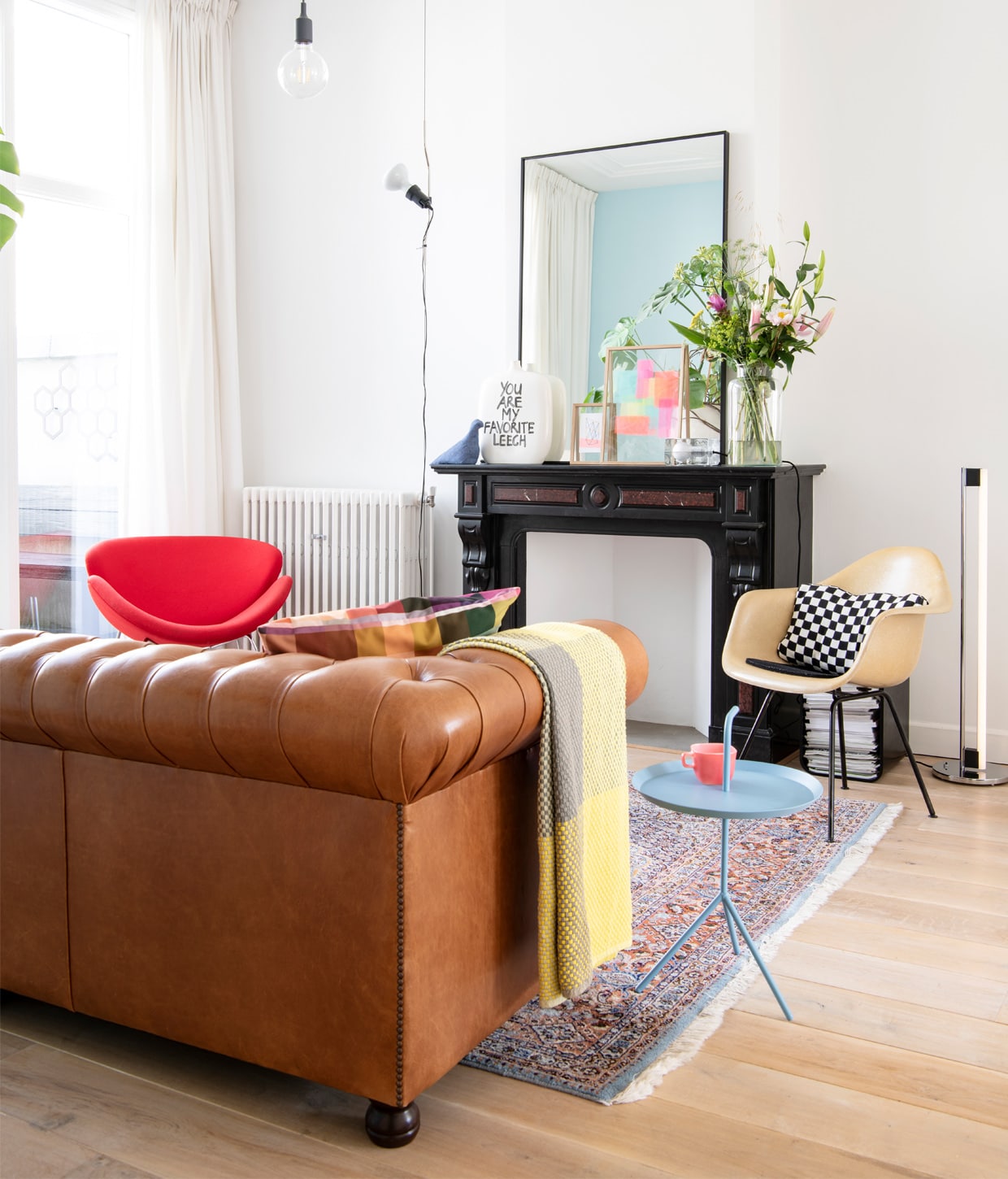 Vogel Kvadrat van Thomas Eyck, vaas You are my favorite leech en kunstwerk It’s all-in your head op blauwe kruk door Birgit, ingelijste kunstwerken Mariadela Araujo, sfeerverlichting Block van Harri Koskinen, vaas Bloemenmagazijn De Iris. Rode en blauwe kruk vintage. Kurken bijzettafel Cork Family model C en stoel Eames DAX van Vitra. Kussen herkomst onbekend. Vloerlamp Eileen Gray Classicon. Hanglamp E27 van Muuto. Vloerkleed Marktplaats.